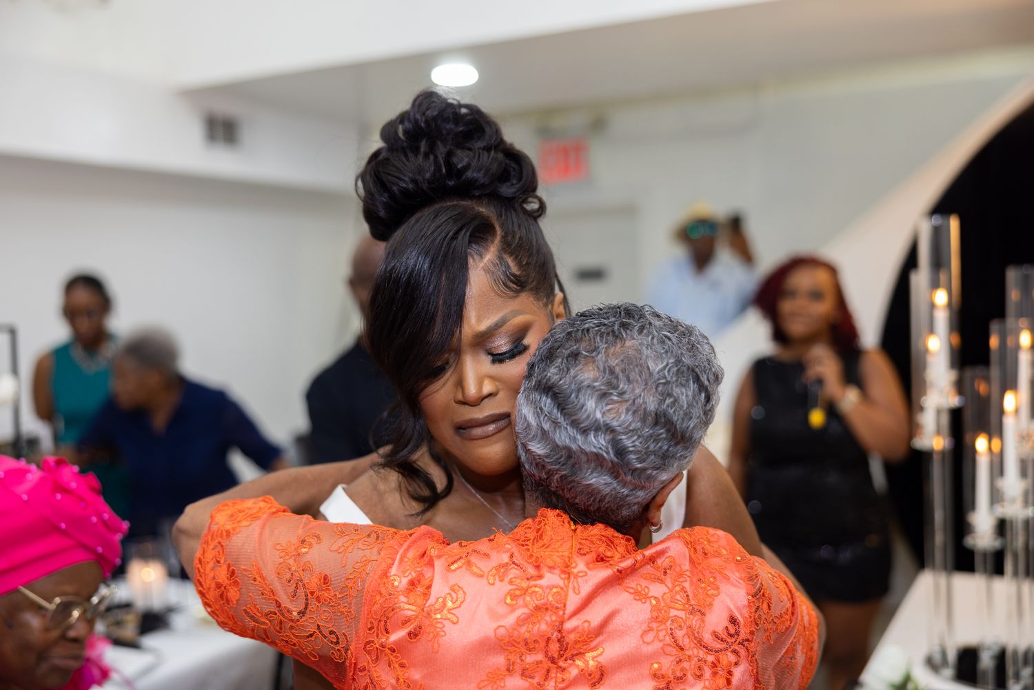 Emotional moment during wedding reception with guests embracing.