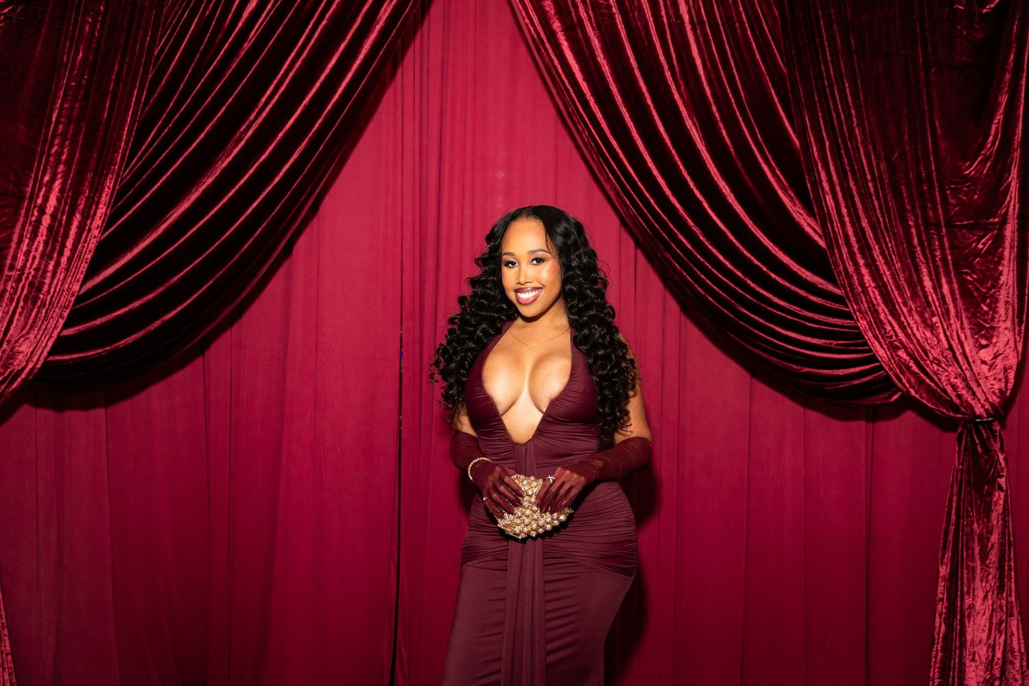 A performer in a sequined dress poses against a deep red velvet curtain backdrop in a glamorous photo series.