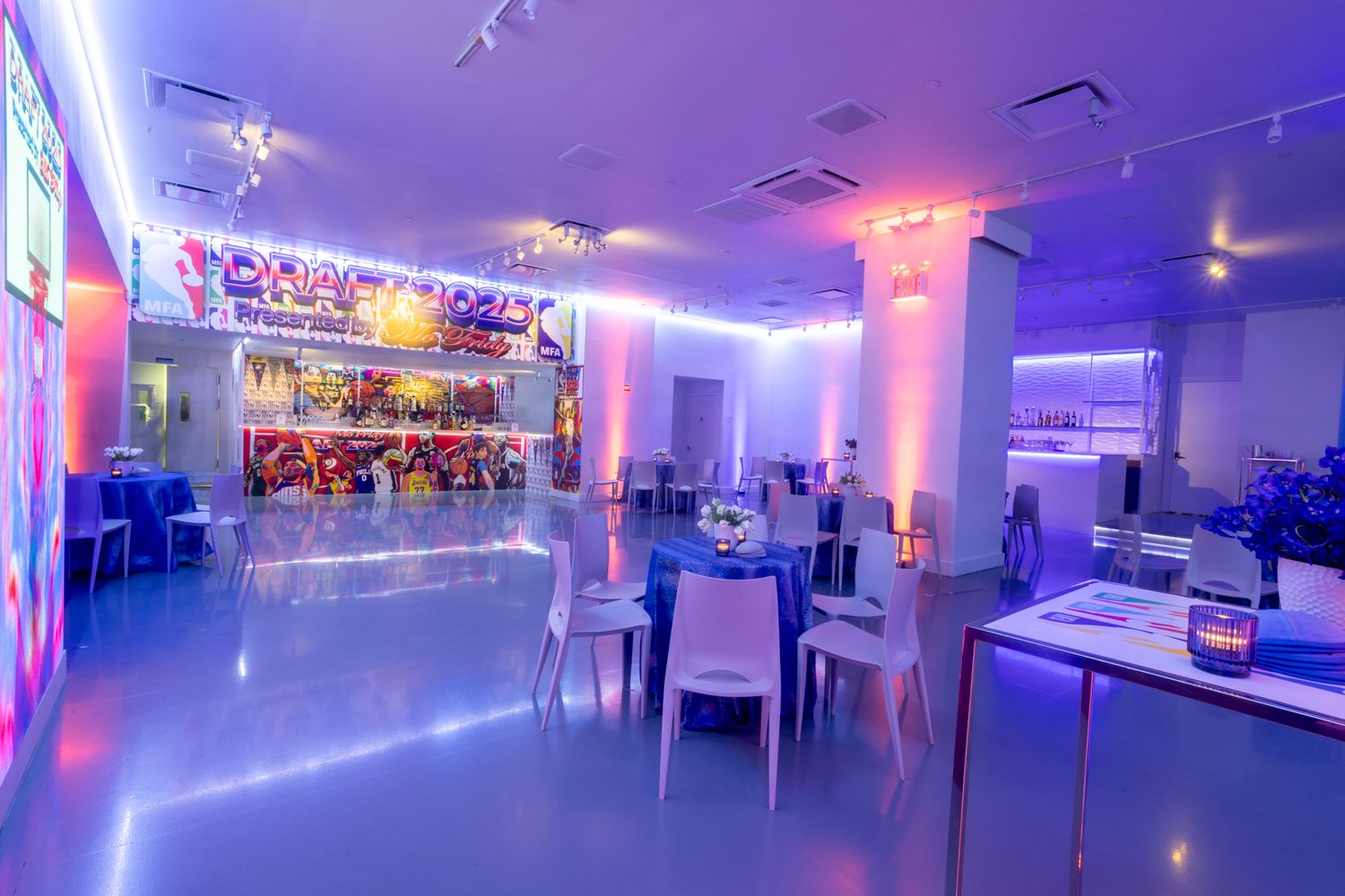 Modern restaurant interior with purple LED lighting, white tables and chairs, and a colorful illuminated bar area.
