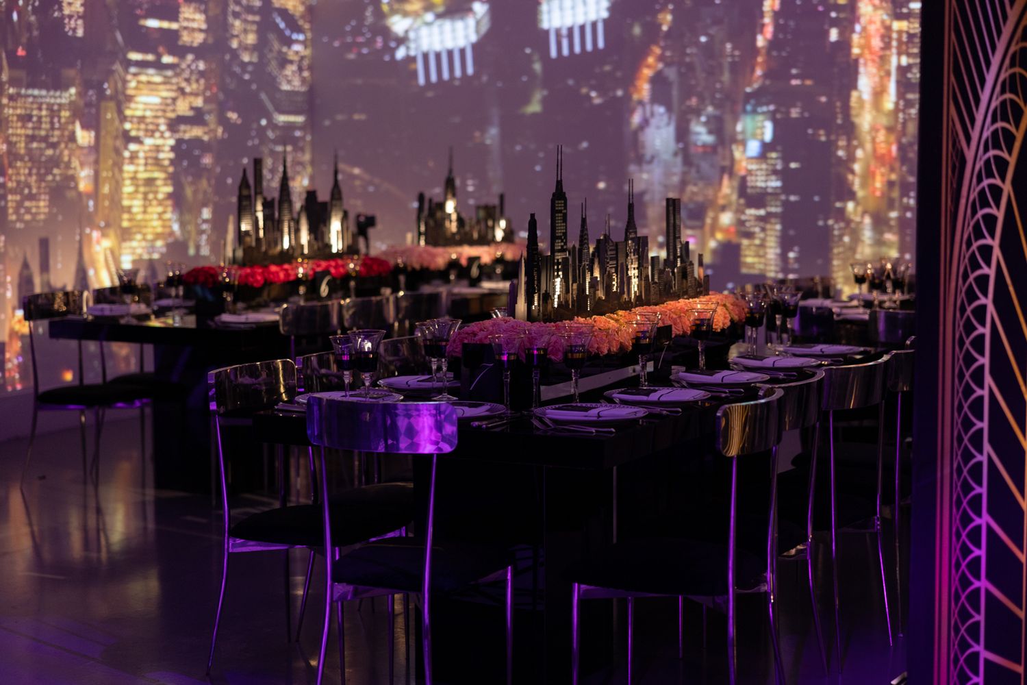 Purple-lit indoor event space with elegant table settings and dramatic architectural lighting design.
