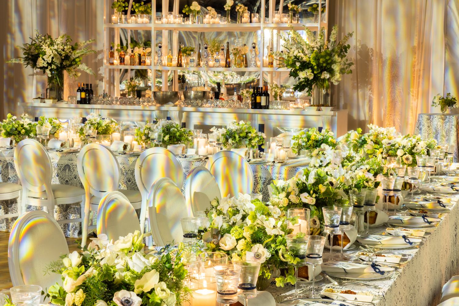 Elegant wedding reception venue with white floral centerpieces and golden lighting creating a luxurious atmosphere.