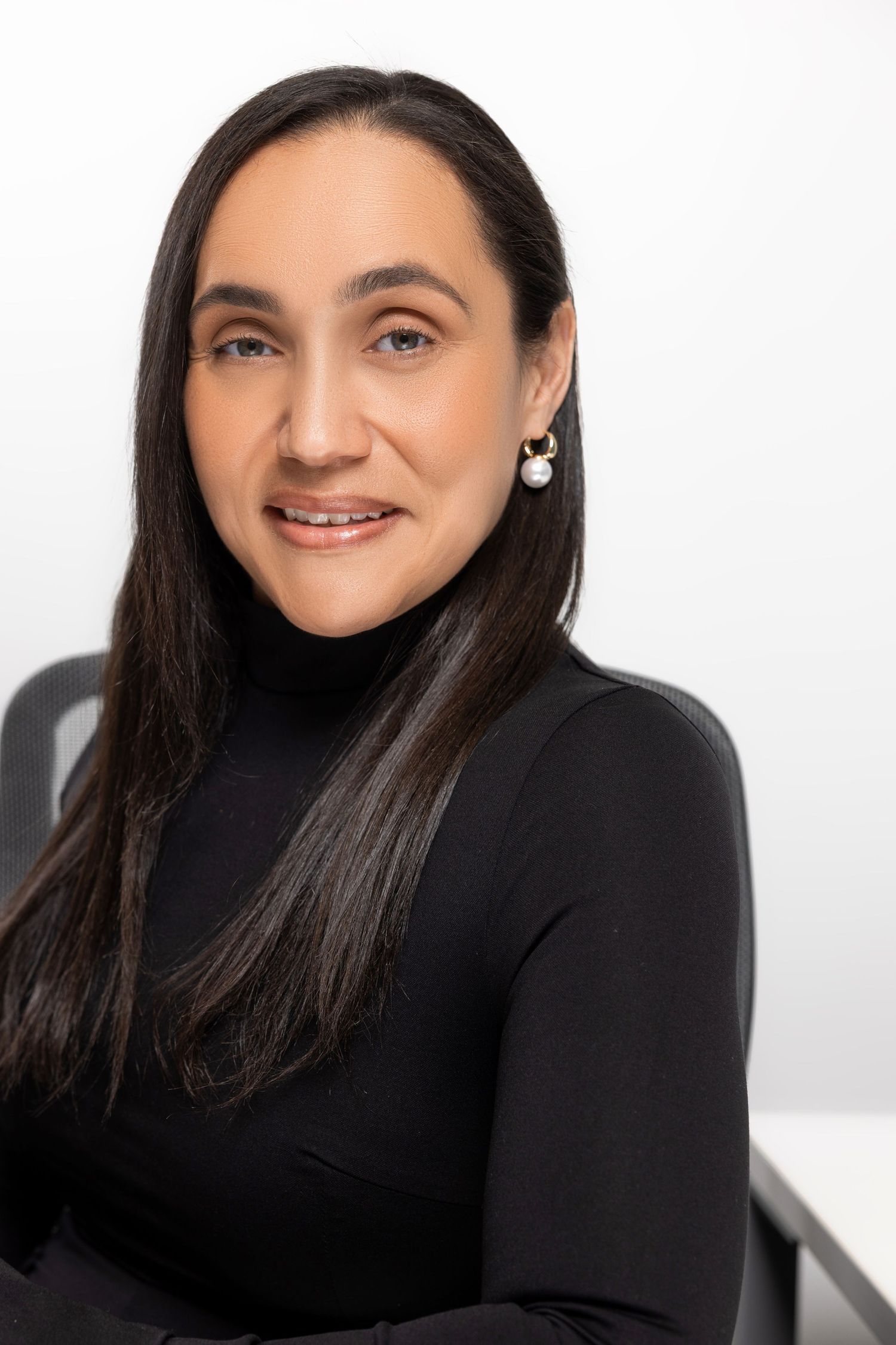 Professional headshot series of a person in a black turtleneck smiling warmly against a light background.
