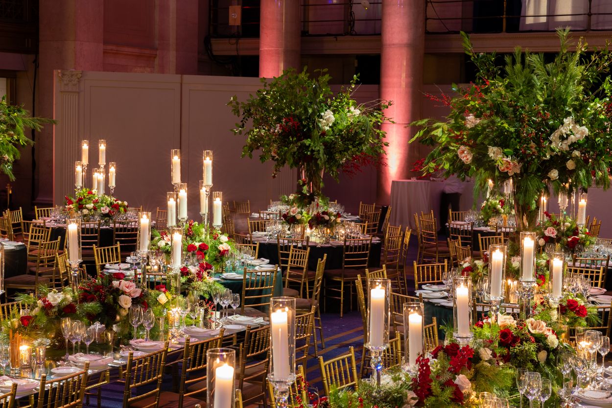 Romantic reception space with candlelit tables, red roses, and warm uplighting creating an intimate atmosphere.