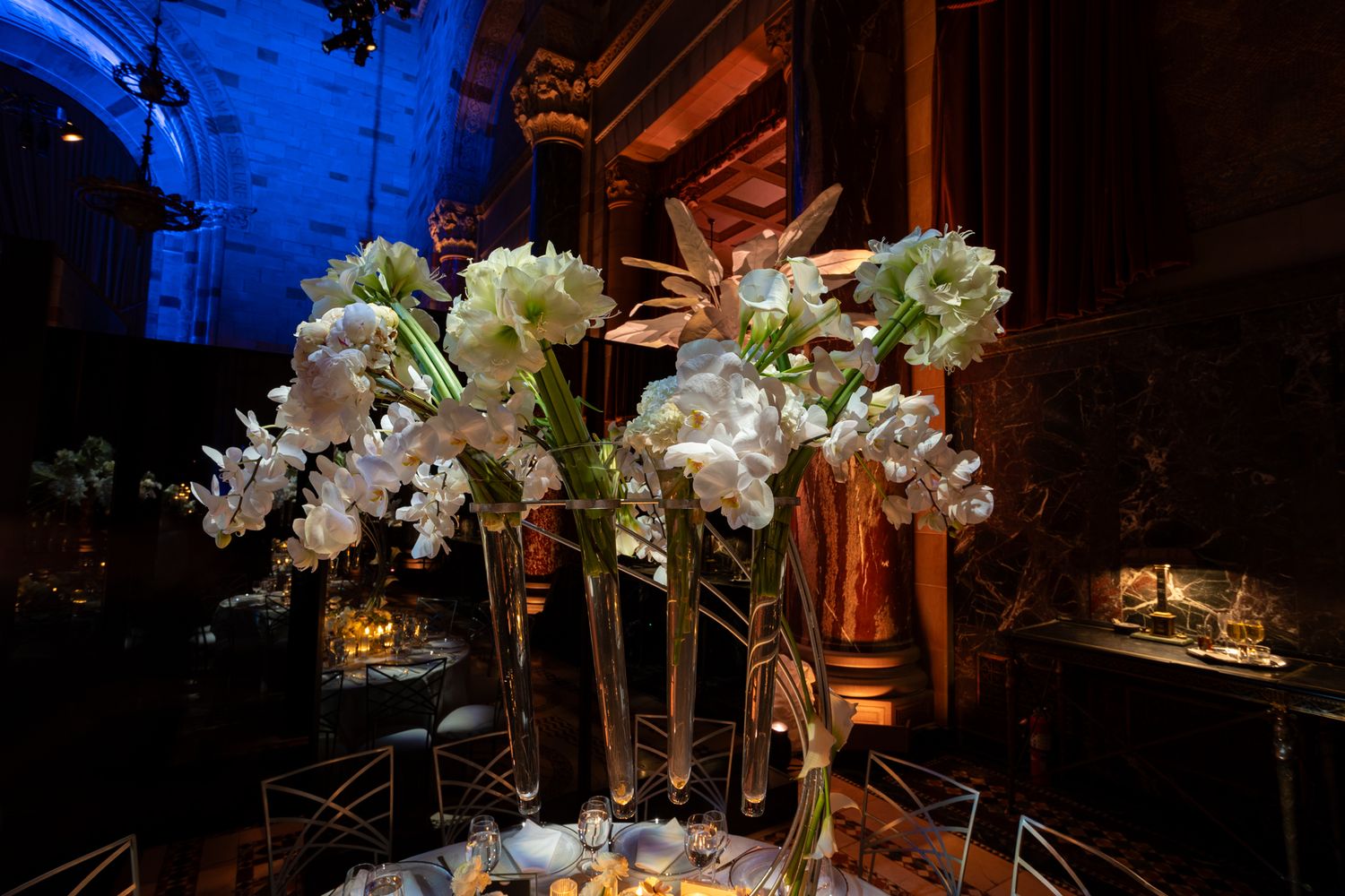 Luxurious banquet hall decorated with crystal chandeliers and white floral arrangements for an evening event.