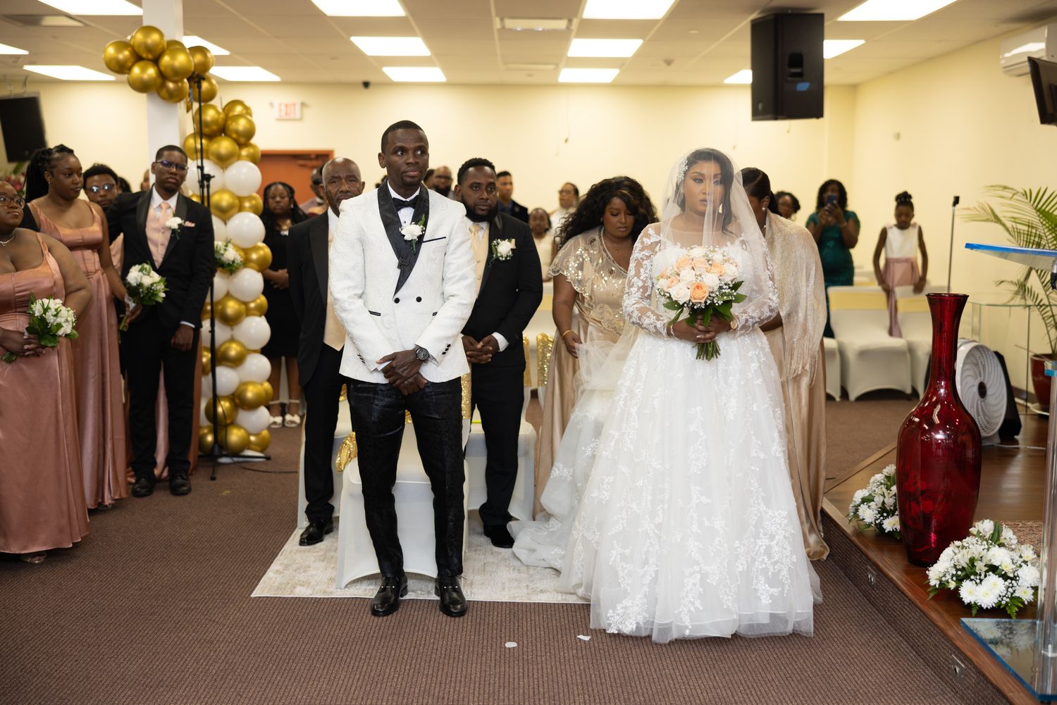 Wedding celebration featuring formal attire and elegant decor with gold balloon accents.