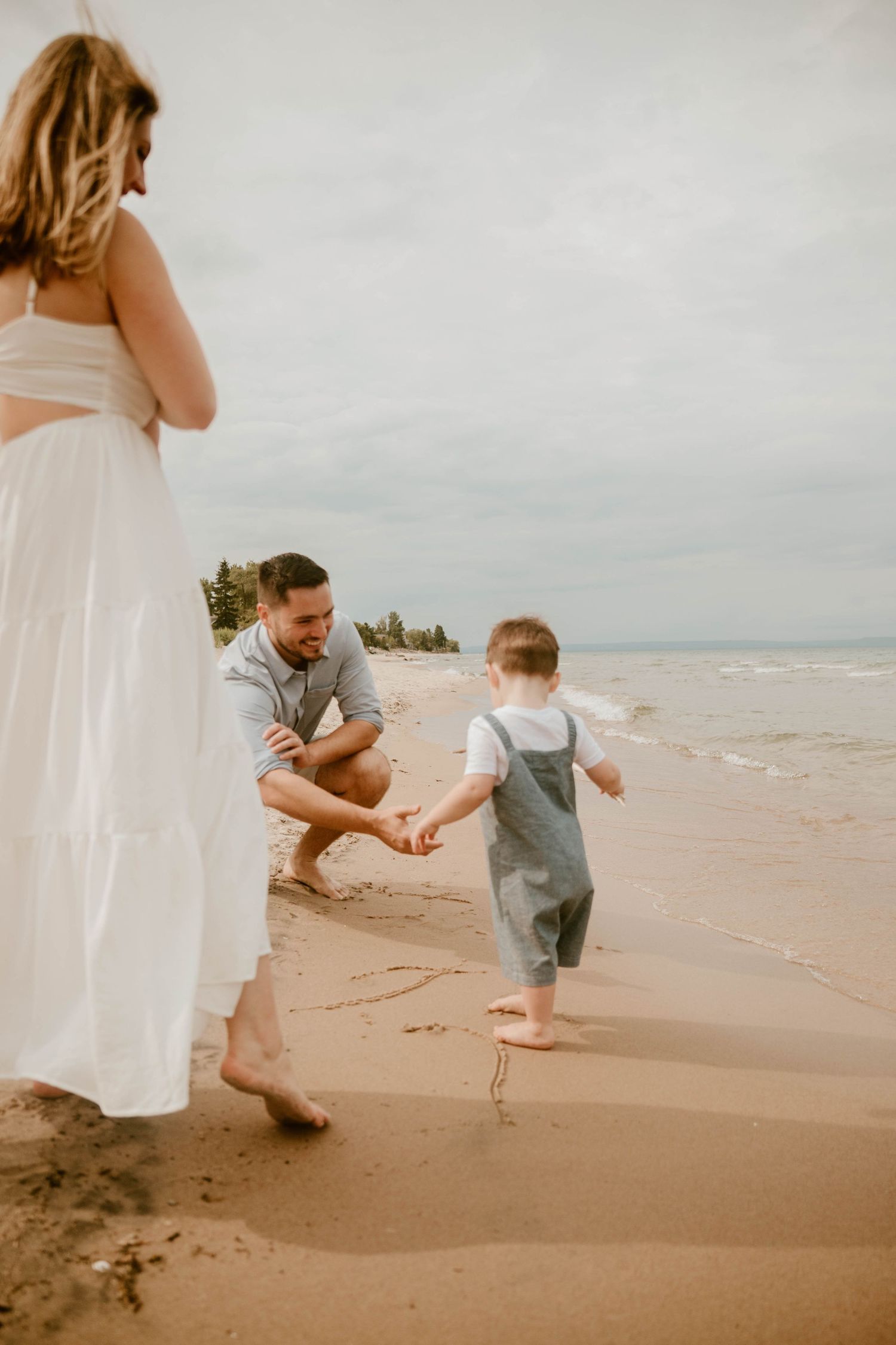 Playful beach moments captured between figures in white and gray clothing on sandy shores.