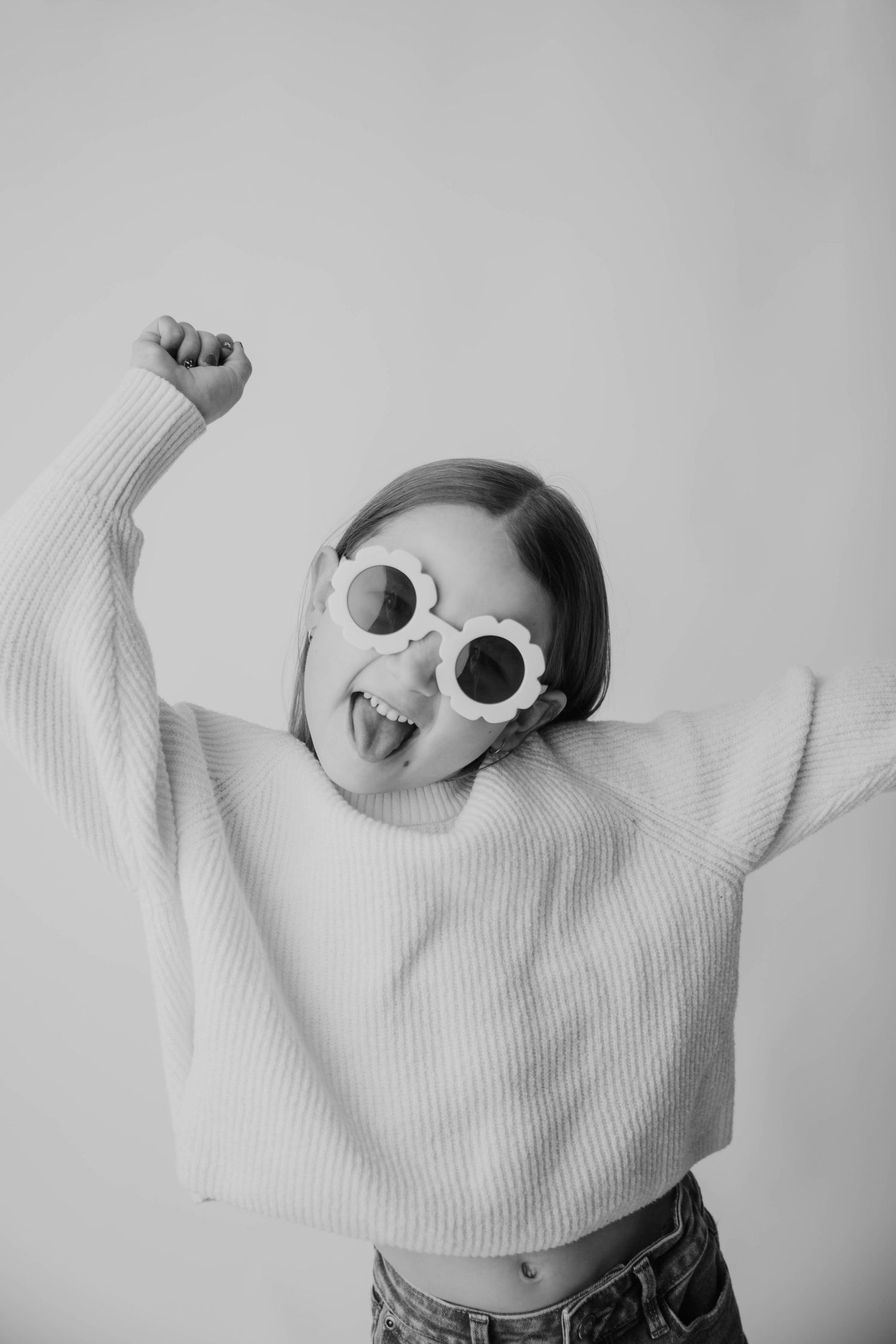 A sequence of black and white photos showing someone in a white sweater dancing and posing playfully against a light background.