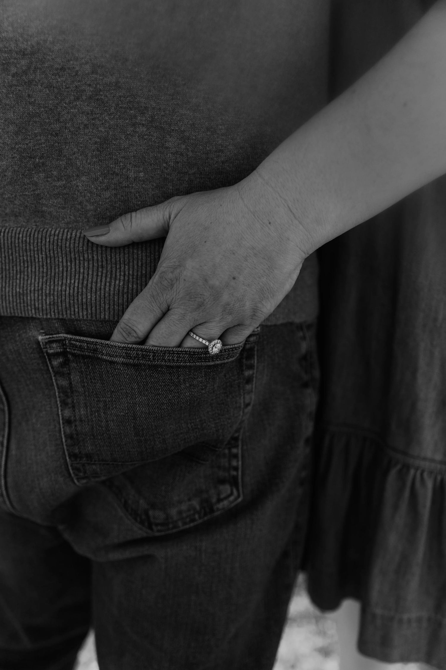 A hand reaches into the back pocket of dark denim jeans in a sequence of black and white photographs to show off engagement ring.