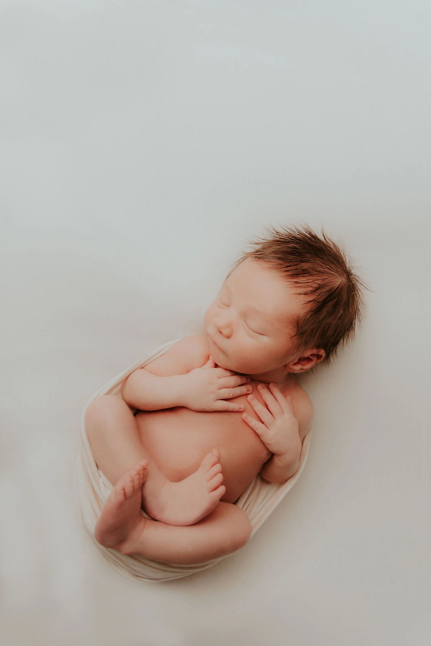 Newborn baby sleeping peacefully in soft natural light.