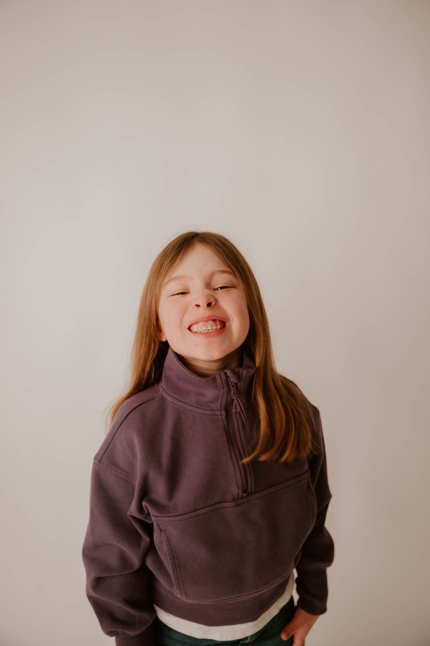 Child wearing a brown turtleneck sweater shown in a playful sequence against a neutral background.