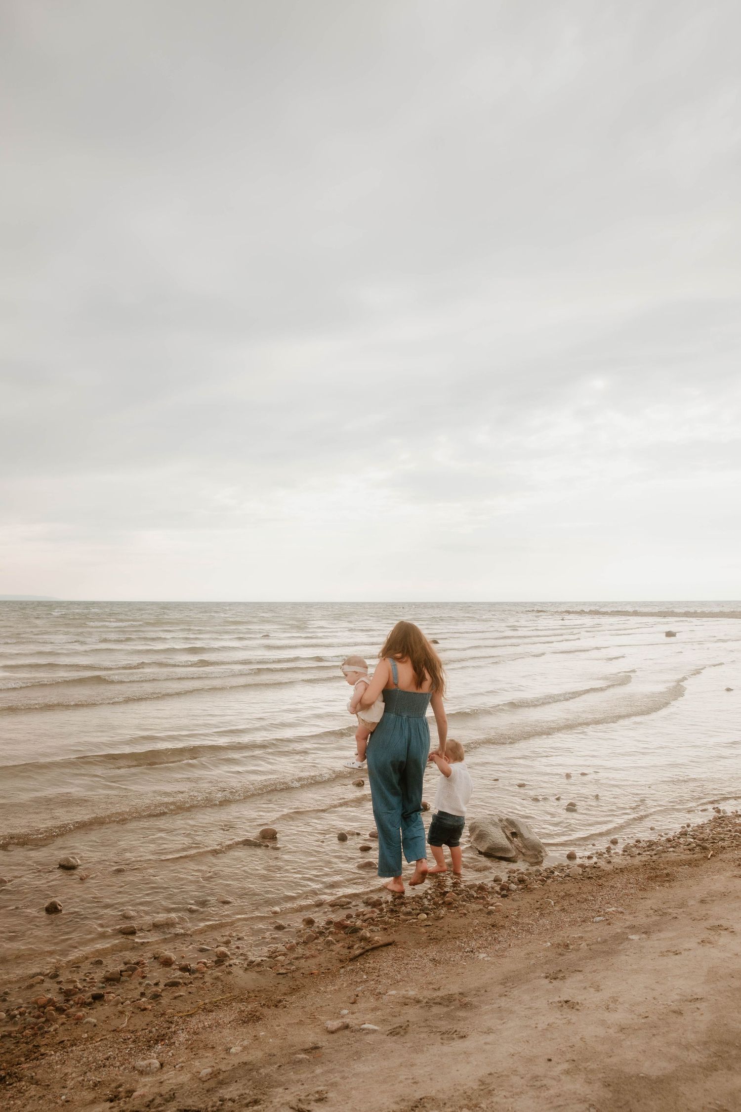 A series of four connected photos showing someone in blue exploring a sandy beach at low tide.