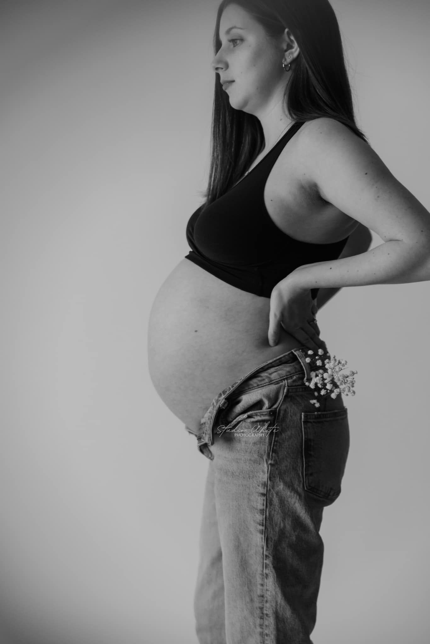 Black and white photo series showing pregnancy progression through side profile silhouettes in denim overalls.