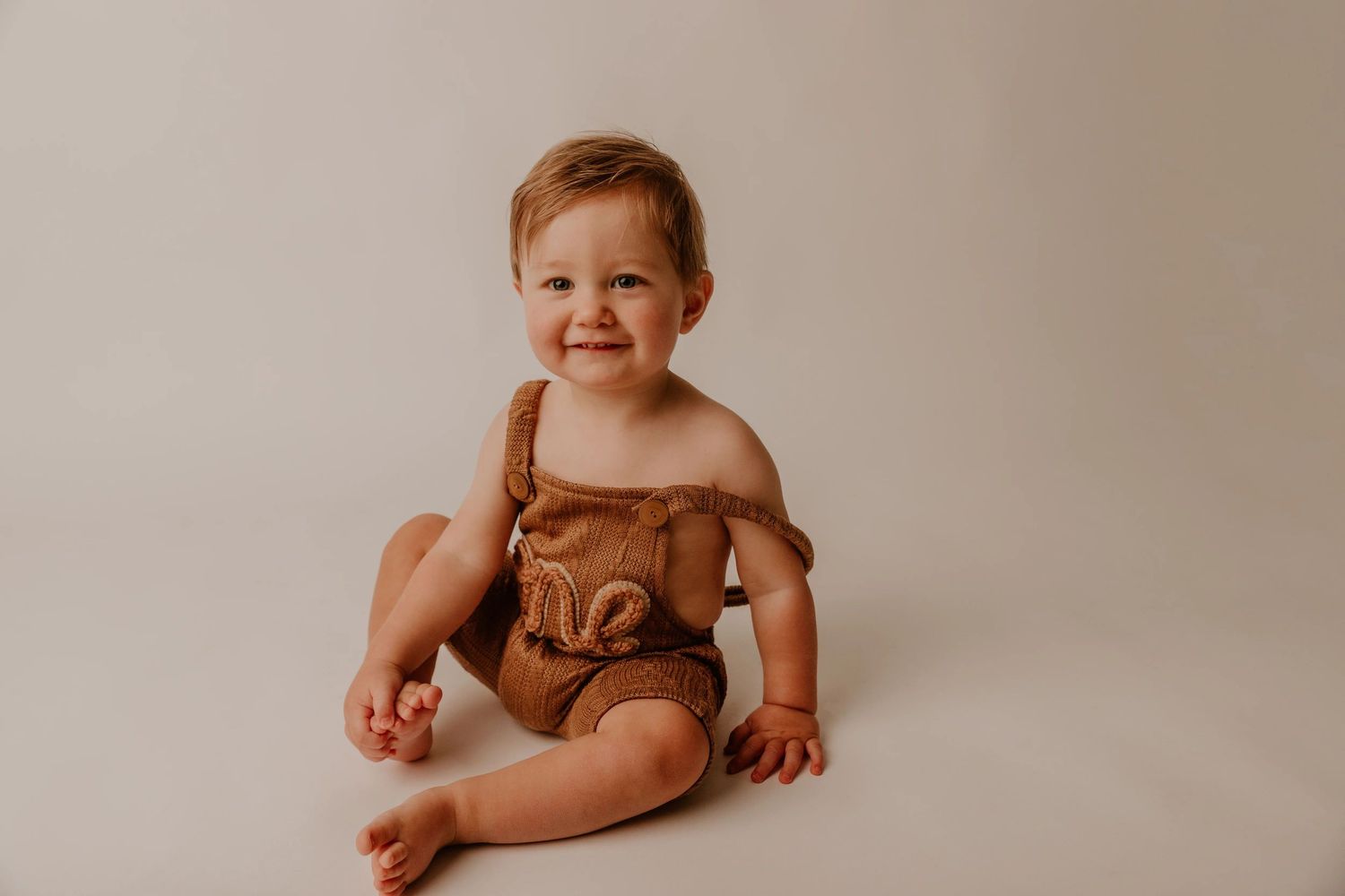 A collection of milestone photos showing a baby's growth and development over their first year in brown tones.