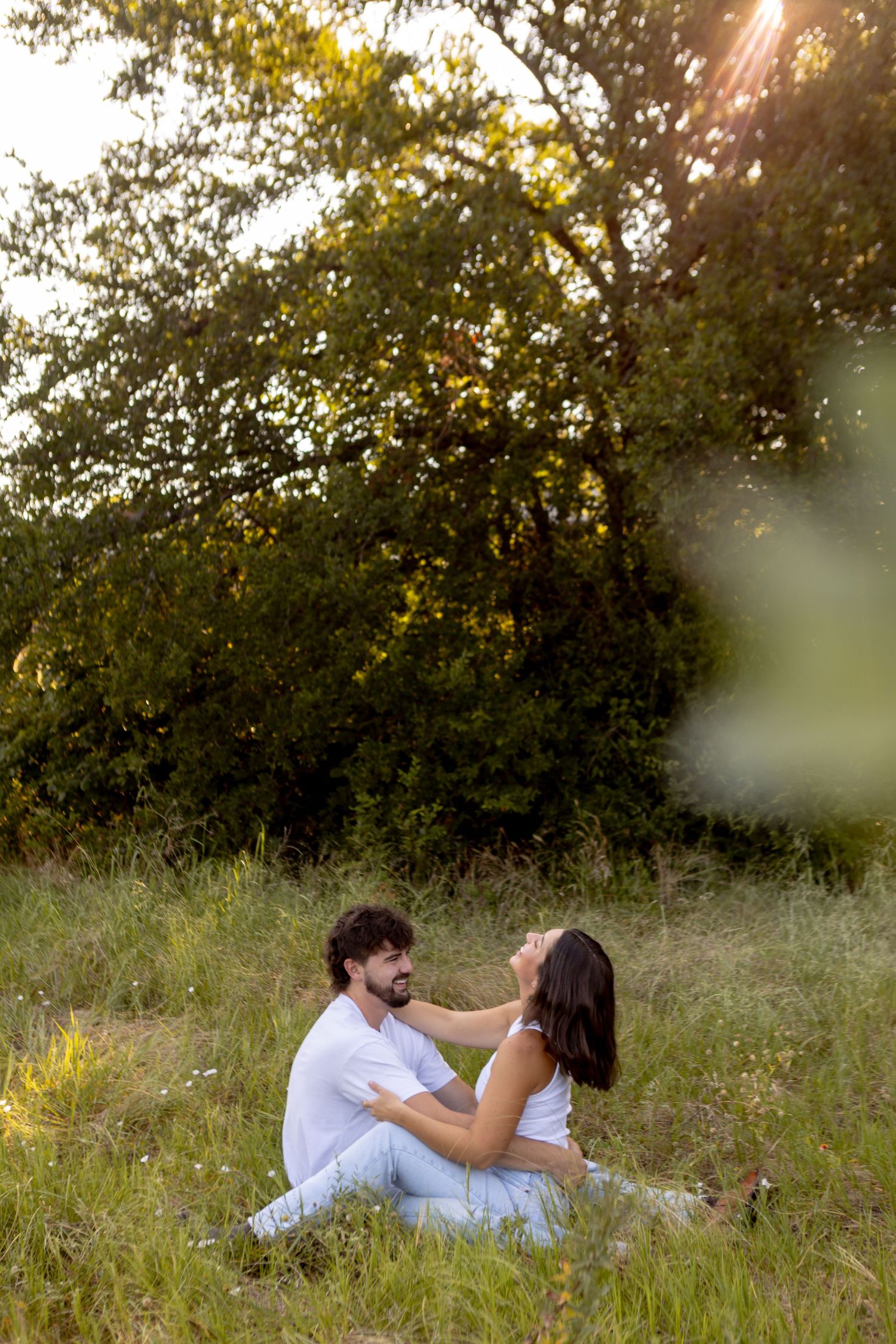 Couple laying in golden sunlit field during sunset photoshoot at a park in McKinney Texas.