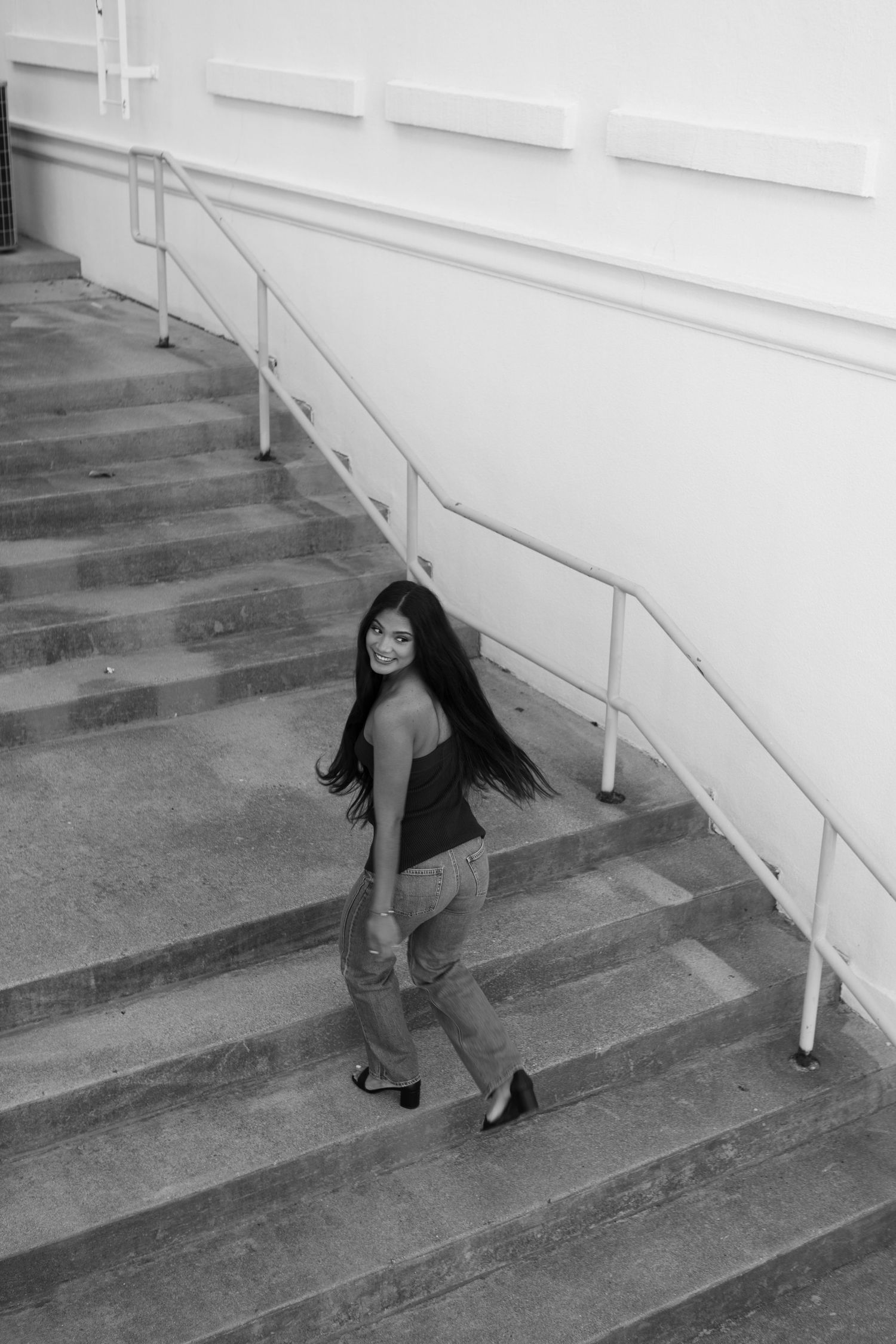 A sequence of black and white photos showing a senior in high school descending concrete stairs with a white wall in Texarkana.