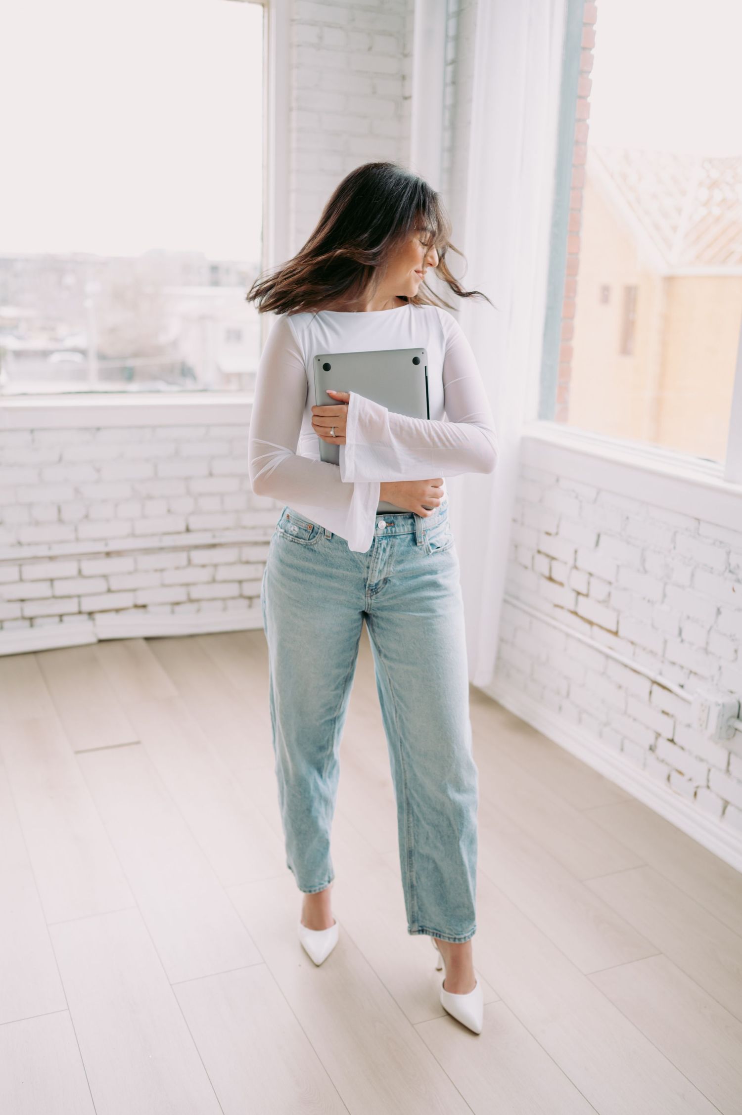 Playful studio portraits with laptop in bright white modern space.
