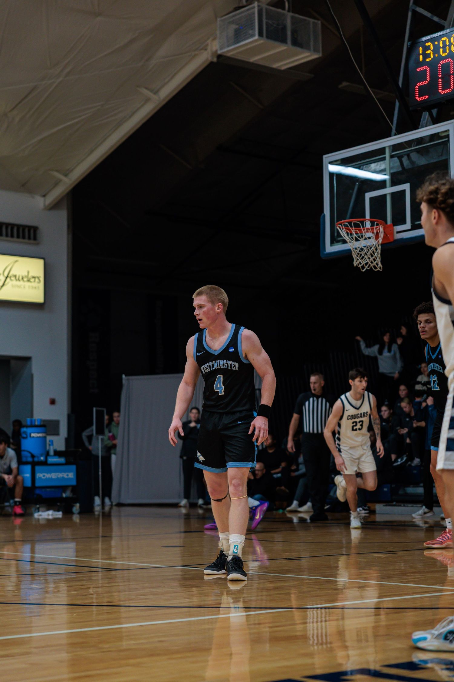 College basketball player number 4 in light blue Westminster uniform on the court during an indoor game.