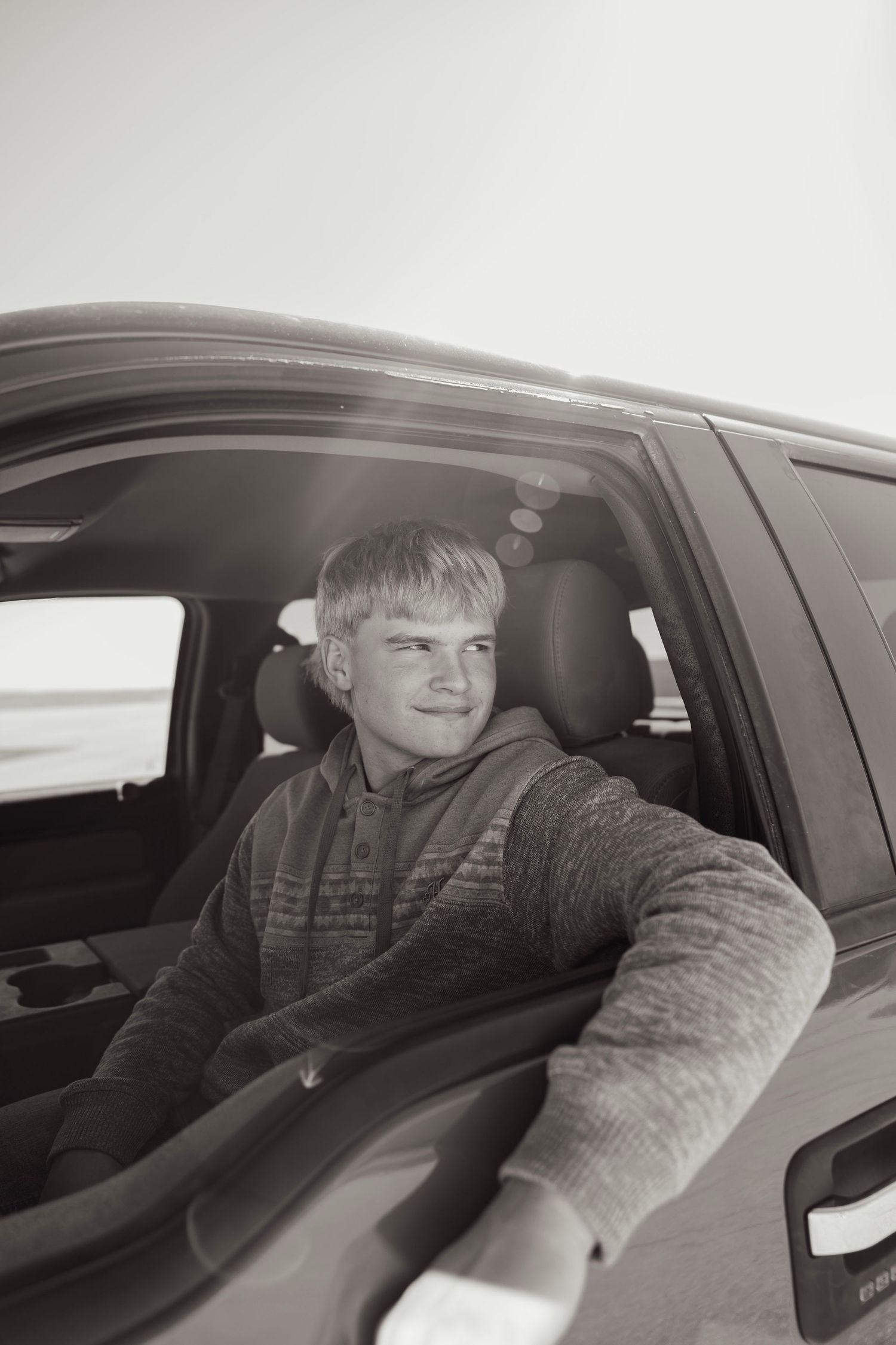 Black and white portrait of teenage boy sitting in truck driver seat.