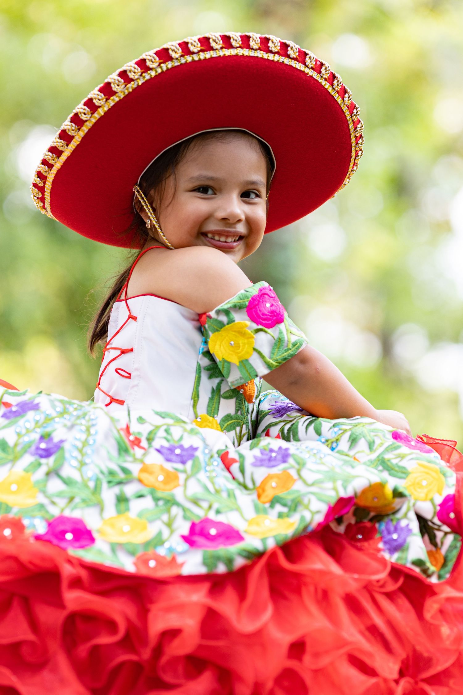 Festive portrait sequence showing traditional Mexican dance costume with bright red and floral details. 3rd birthday portrait session.