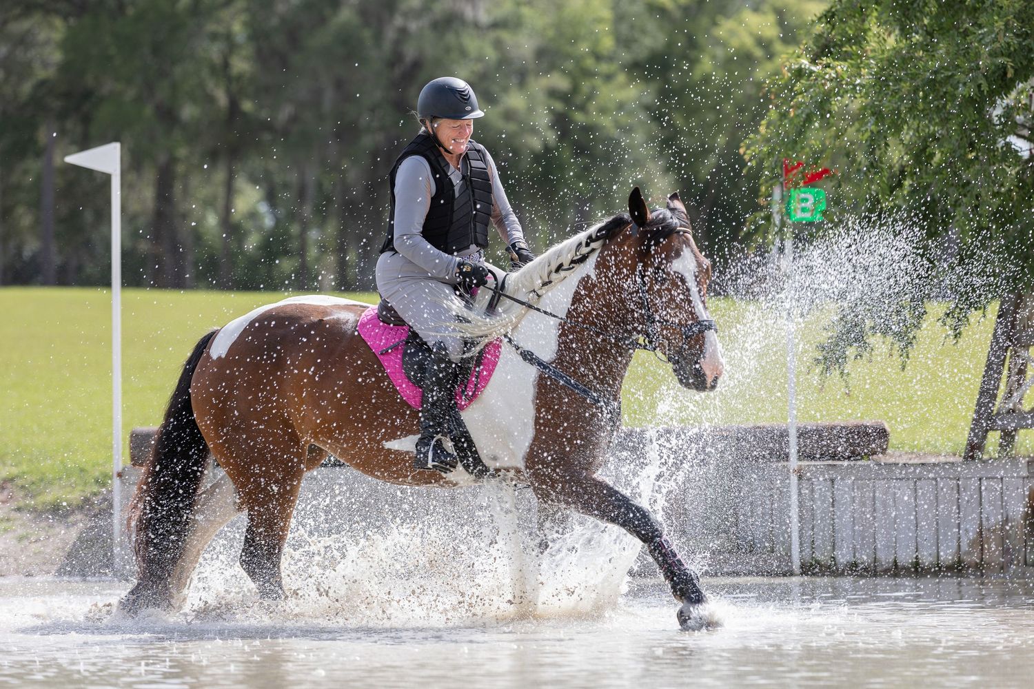 Horse and rider splashing through water during cross country jumping course during an evening clinic at Majestic Oaks, Reddick Florida.