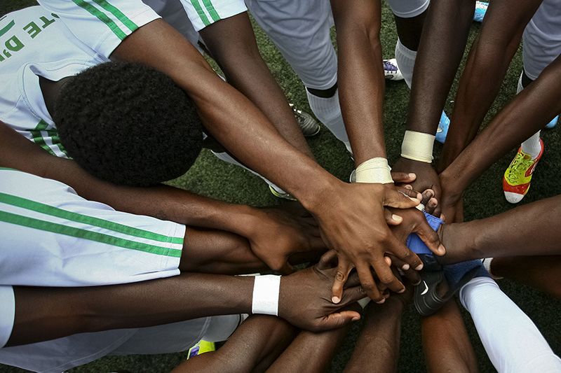Soccer players joining hands in prayer before the match — emotional pre-game ritual captured with photojournalistic style.
