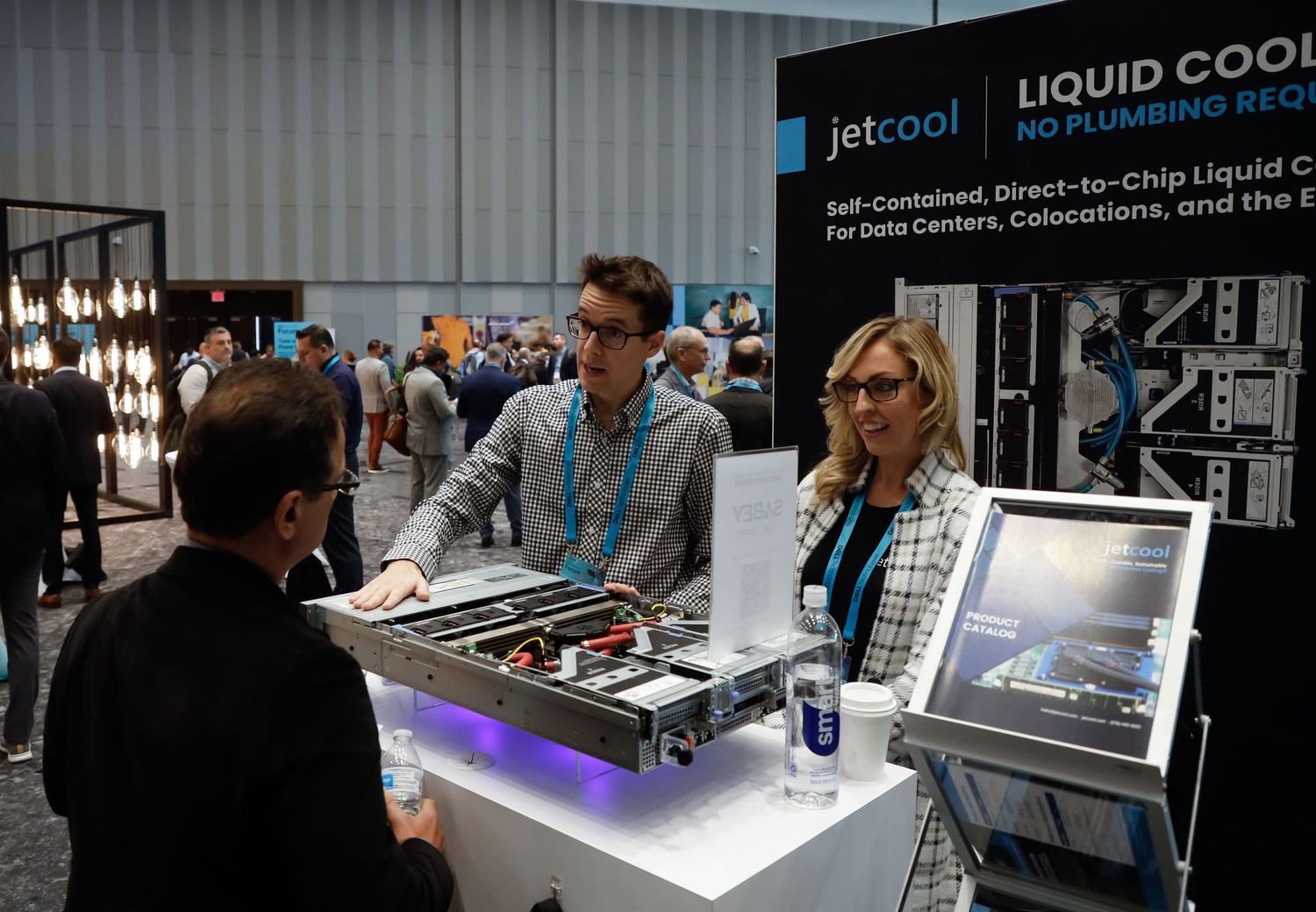 Computer hardware enthusiasts examine liquid cooling components and gaming PC builds at a technology trade show display at NYC Javit Center