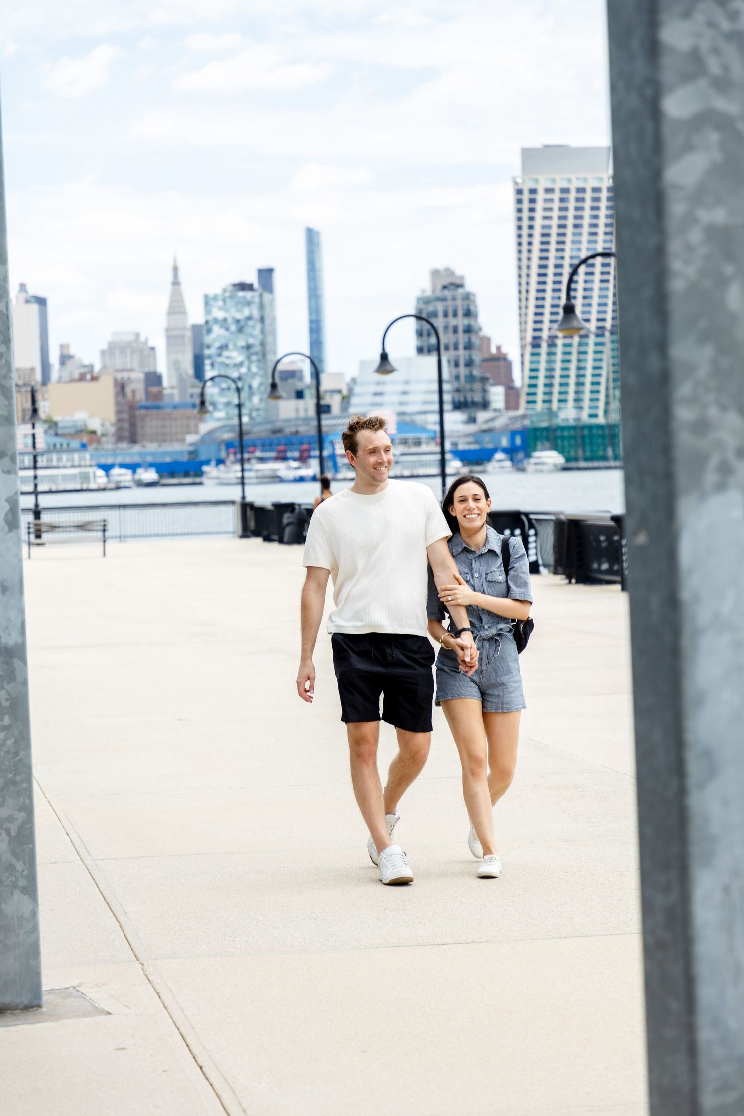 Candid couple portrait on Hoboken waterfront pier — storytelling photography with Manhattan skyline view.