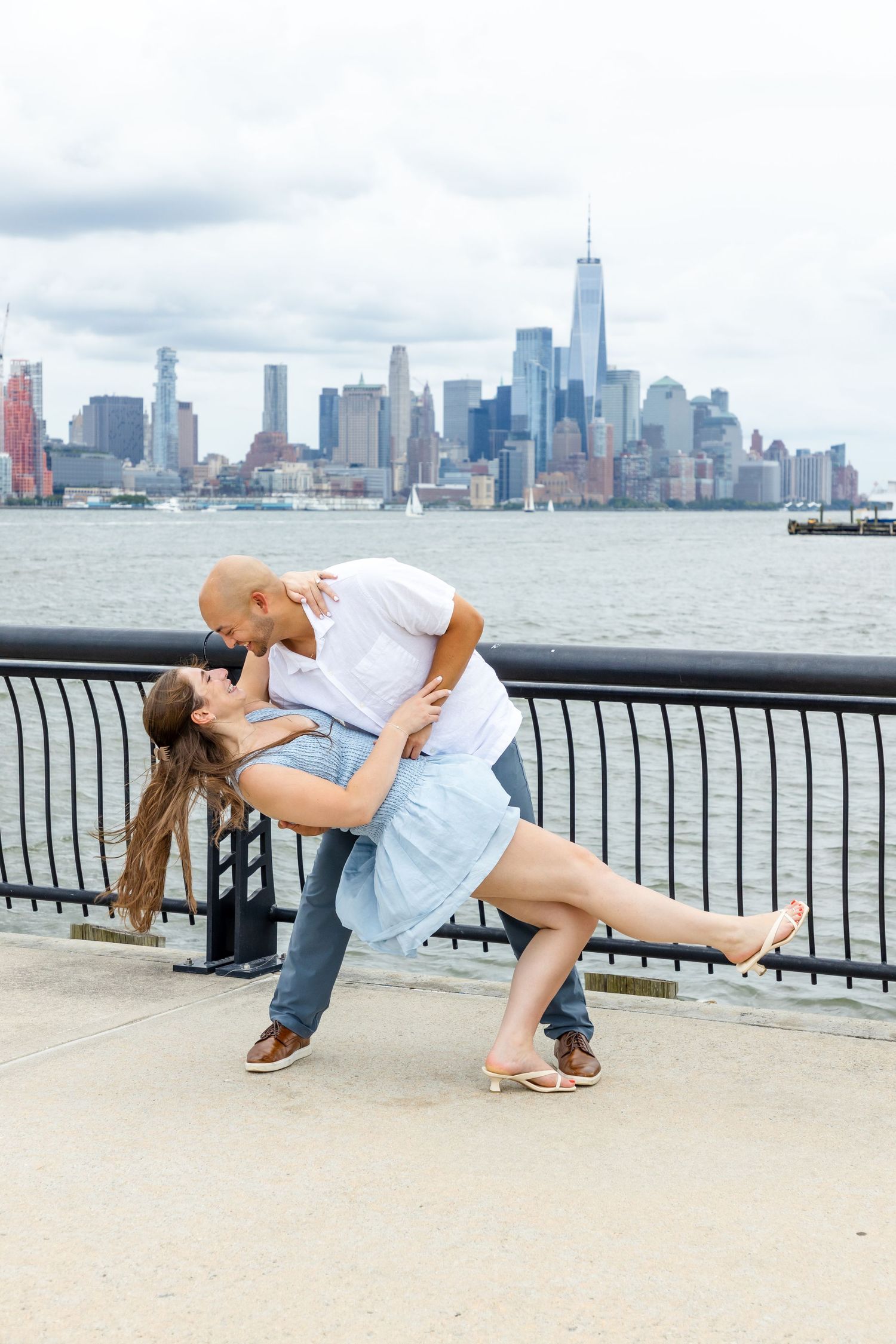 Waterfront surprise proposal photography at Exchange Place, Jersey City, with the Manhattan skyline in the background