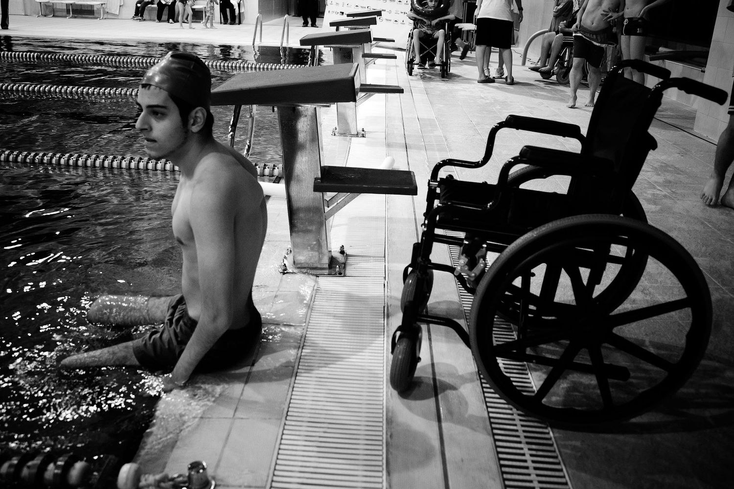 Young swimmer with a disability preparing to enter the pool — powerful image of determination and inclusion in youth sports.