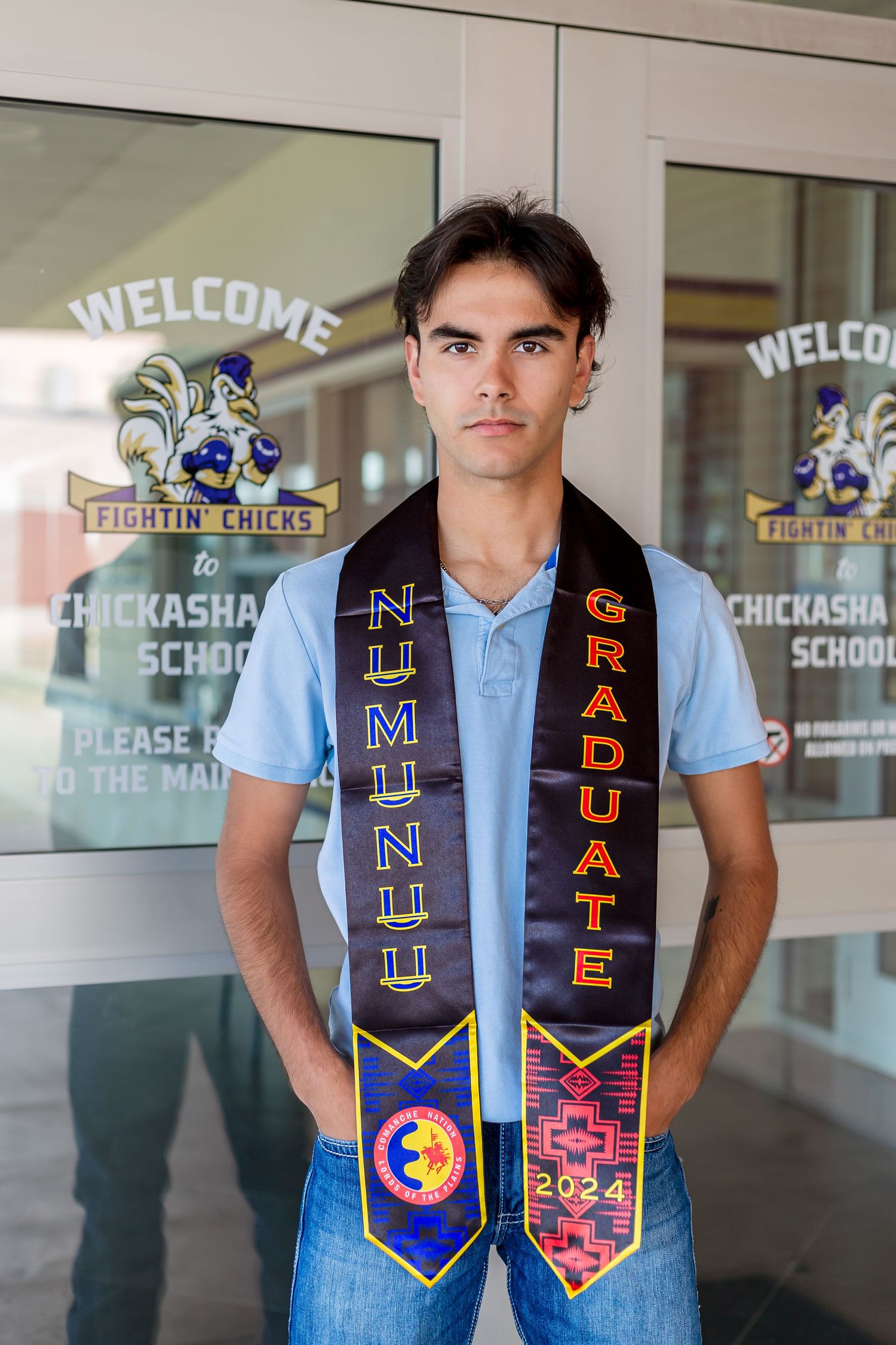 Graduate wearing traditional blue graduation stole with Native American designs and symbols.
