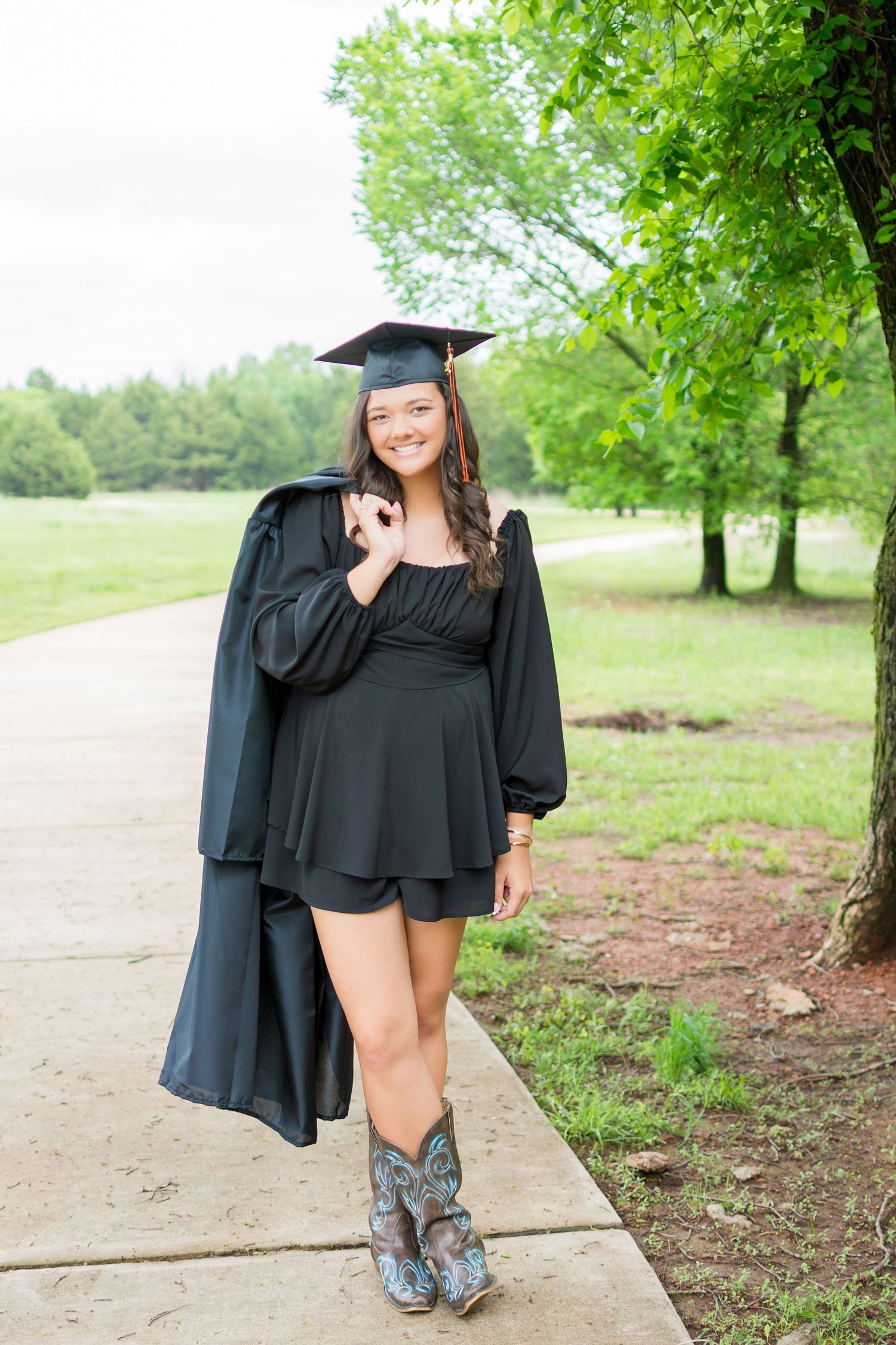 Graduation photos featuring a black cap and gown on a tree-lined path.