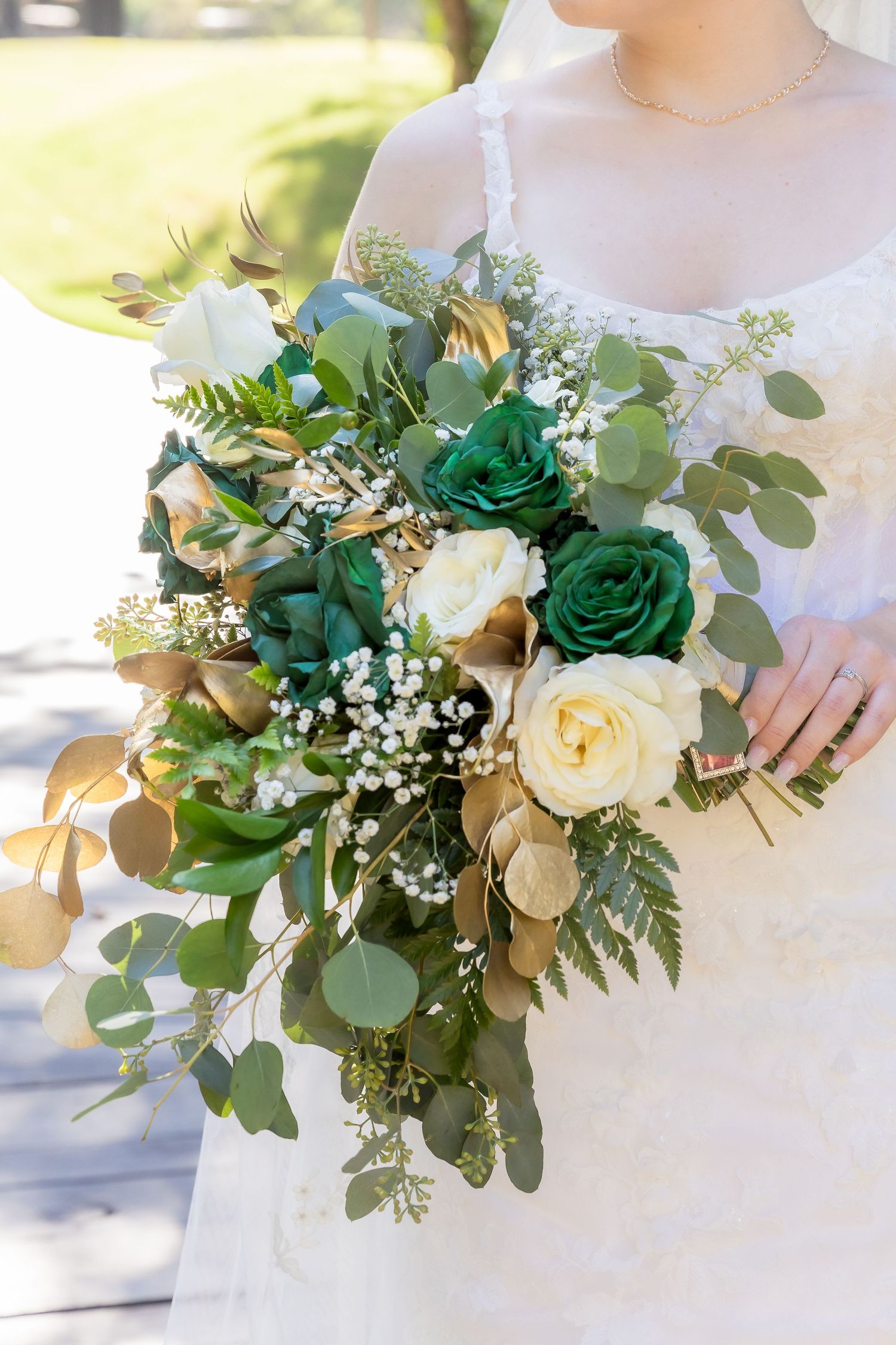 Elegant wedding bouquet featuring green roses, white flowers, and eucalyptus leaves against a light background.