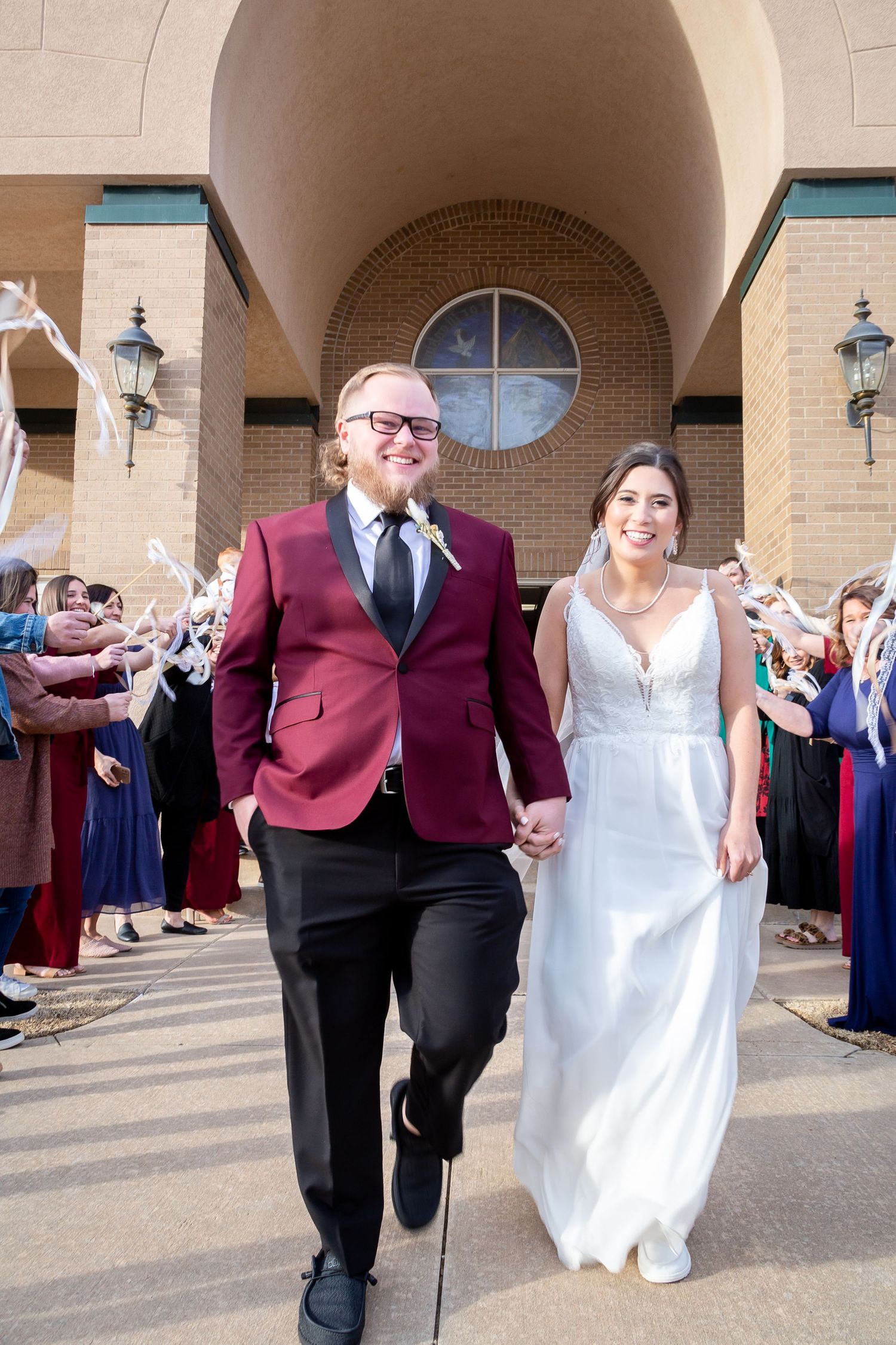 A newlywed couple exits their wedding ceremony as guests line the walkway with sparklers at a church entrance.