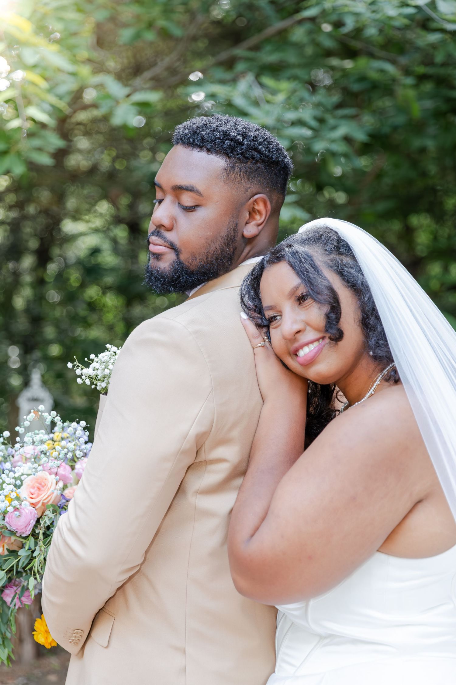 A happy couple shares an intimate moment on their wedding day in a garden setting, surrounded by soft, natural lighting.