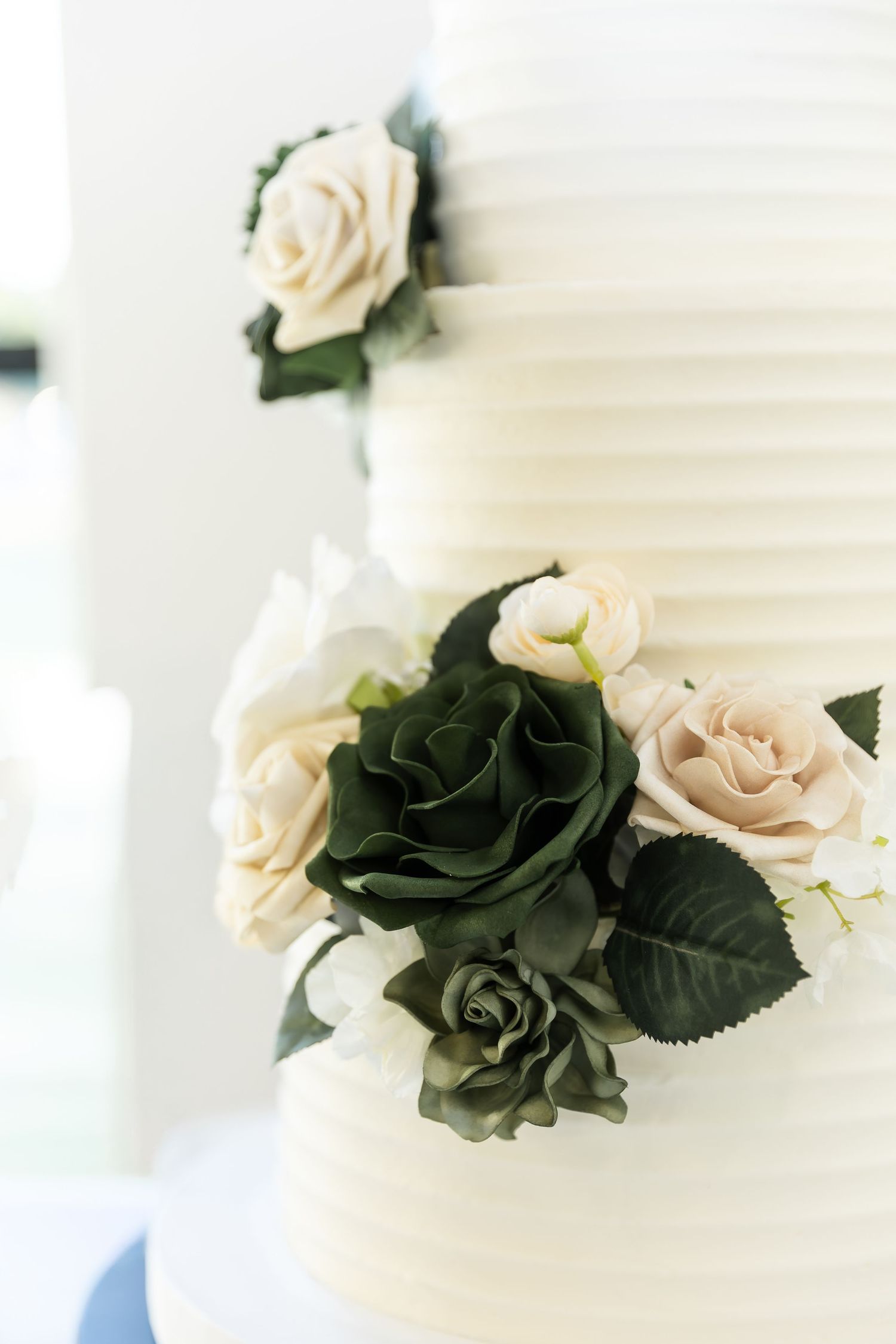 Elegant white wedding cake decorated with black and blush pink roses.
