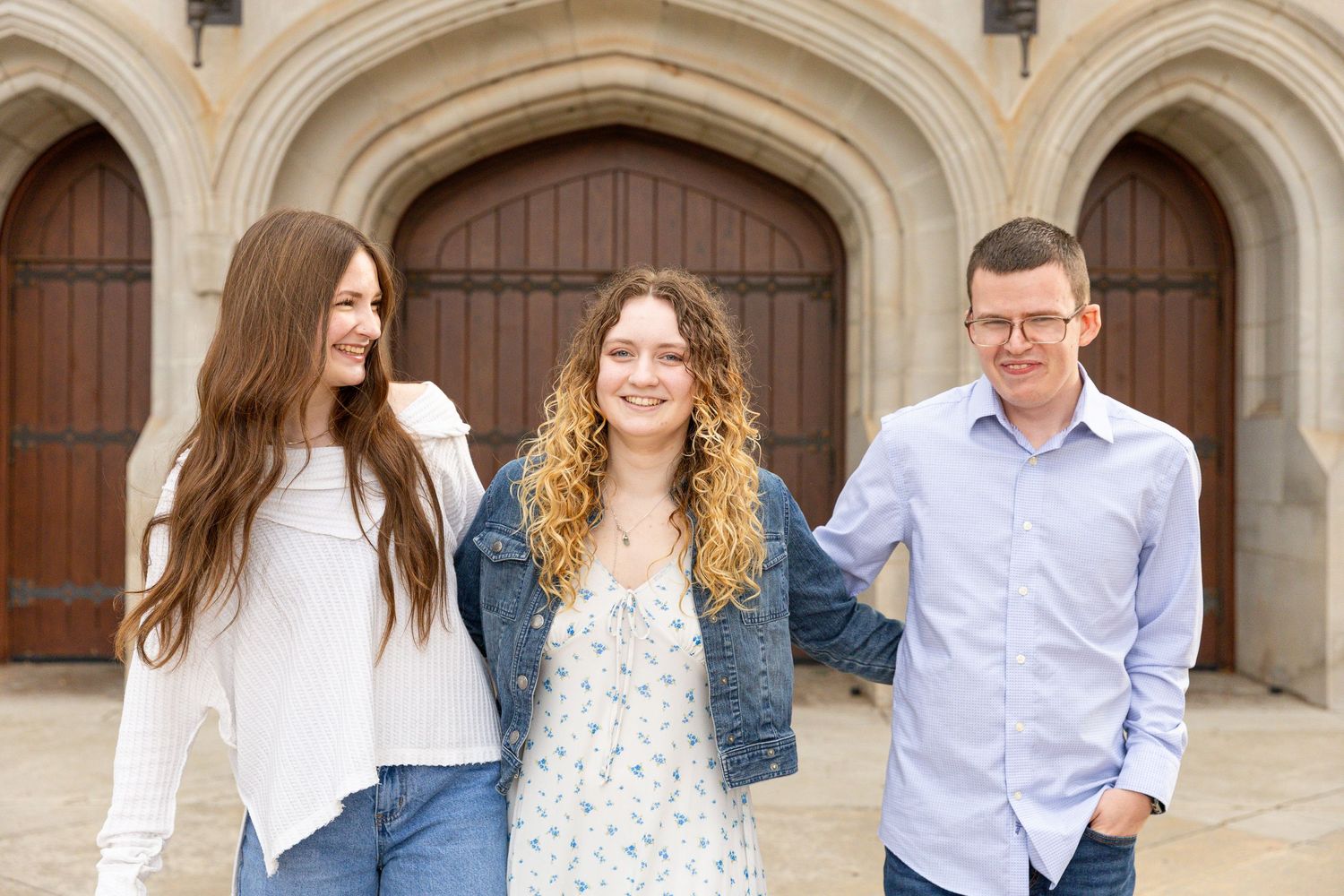 Casual family portrait session in front of gothic stone architecture with wooden doors.
