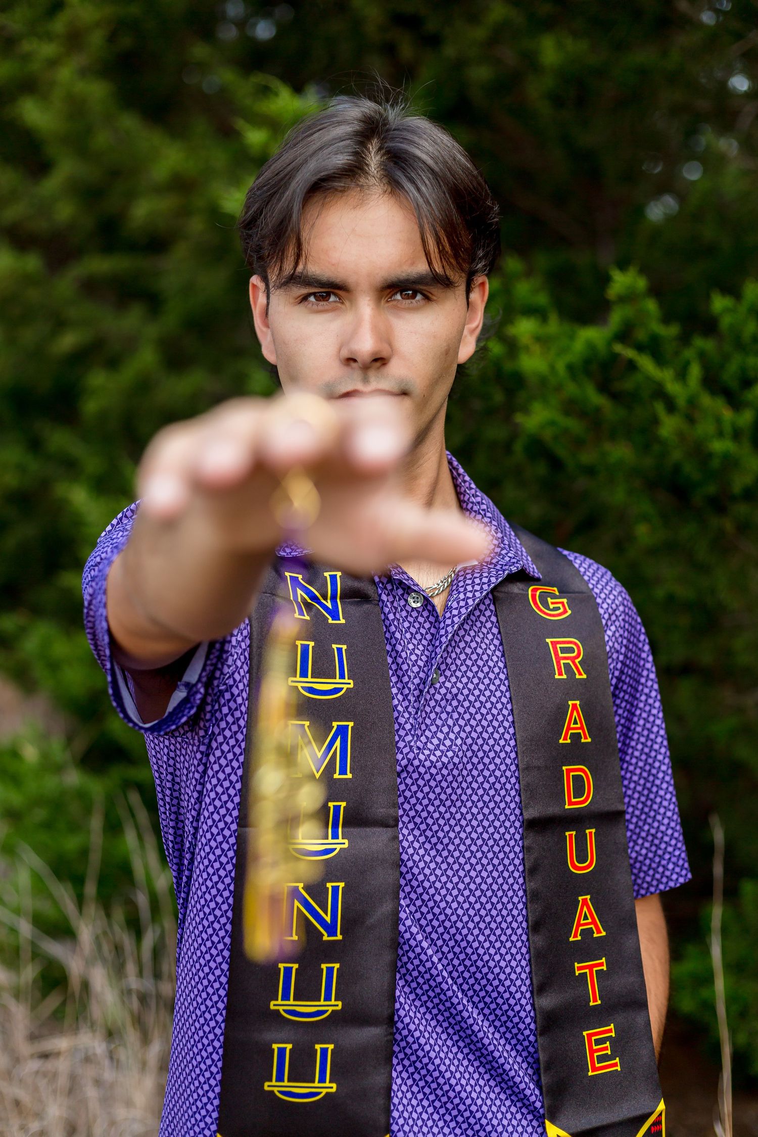 Senior in a purple polka dot jersey, pointing at the camera in an outdoor setting.