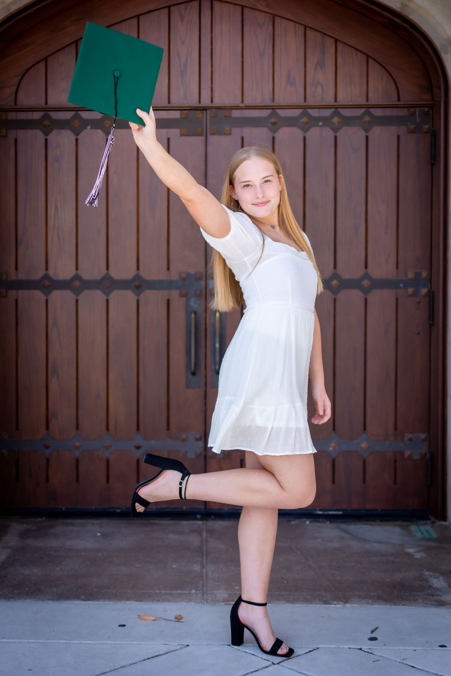 Dynamic dance-inspired senior poses against wooden garage door background in white outfit.
