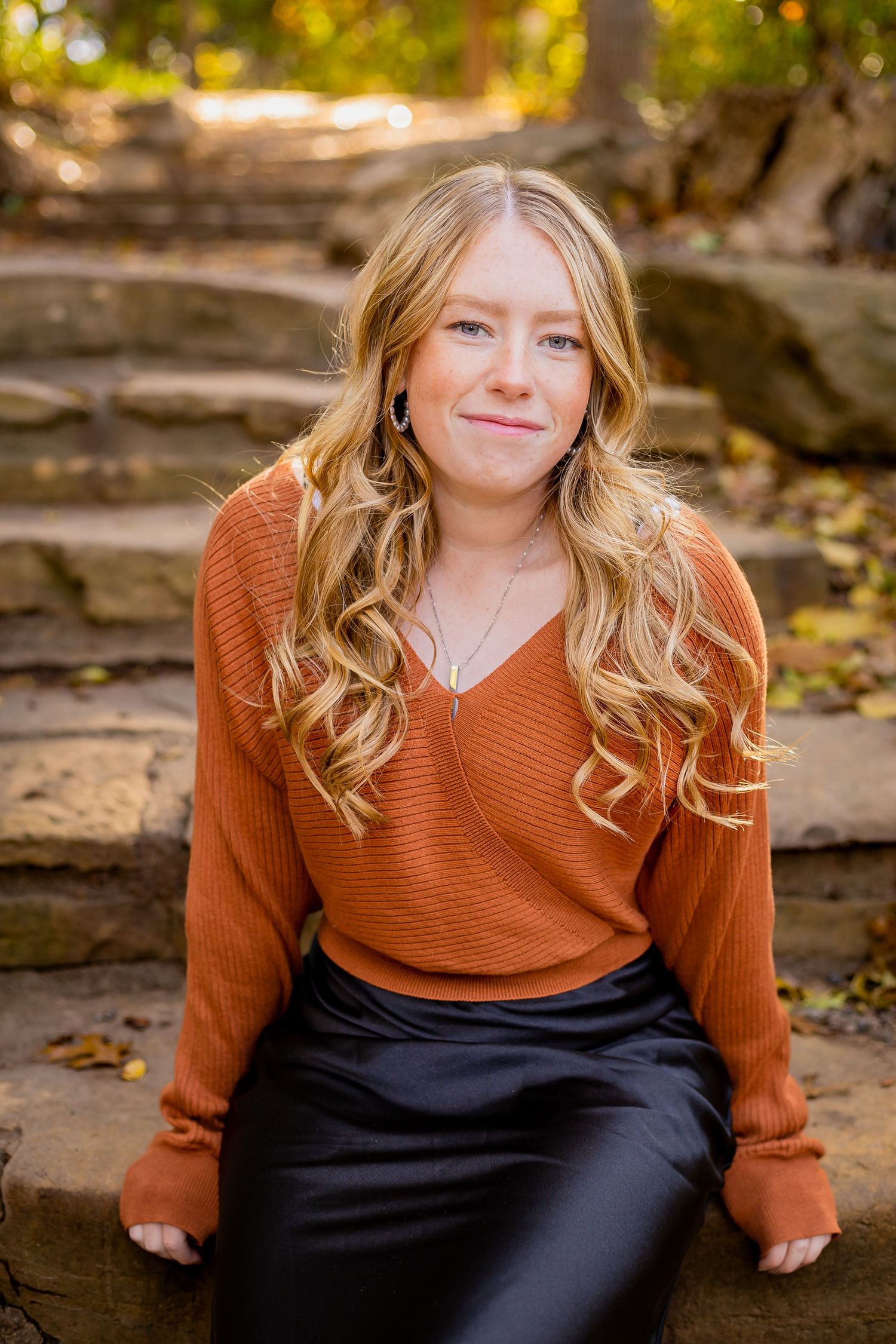 Casual outdoor senior portrait session featuring a rust-colored sweater and natural autumn lighting.