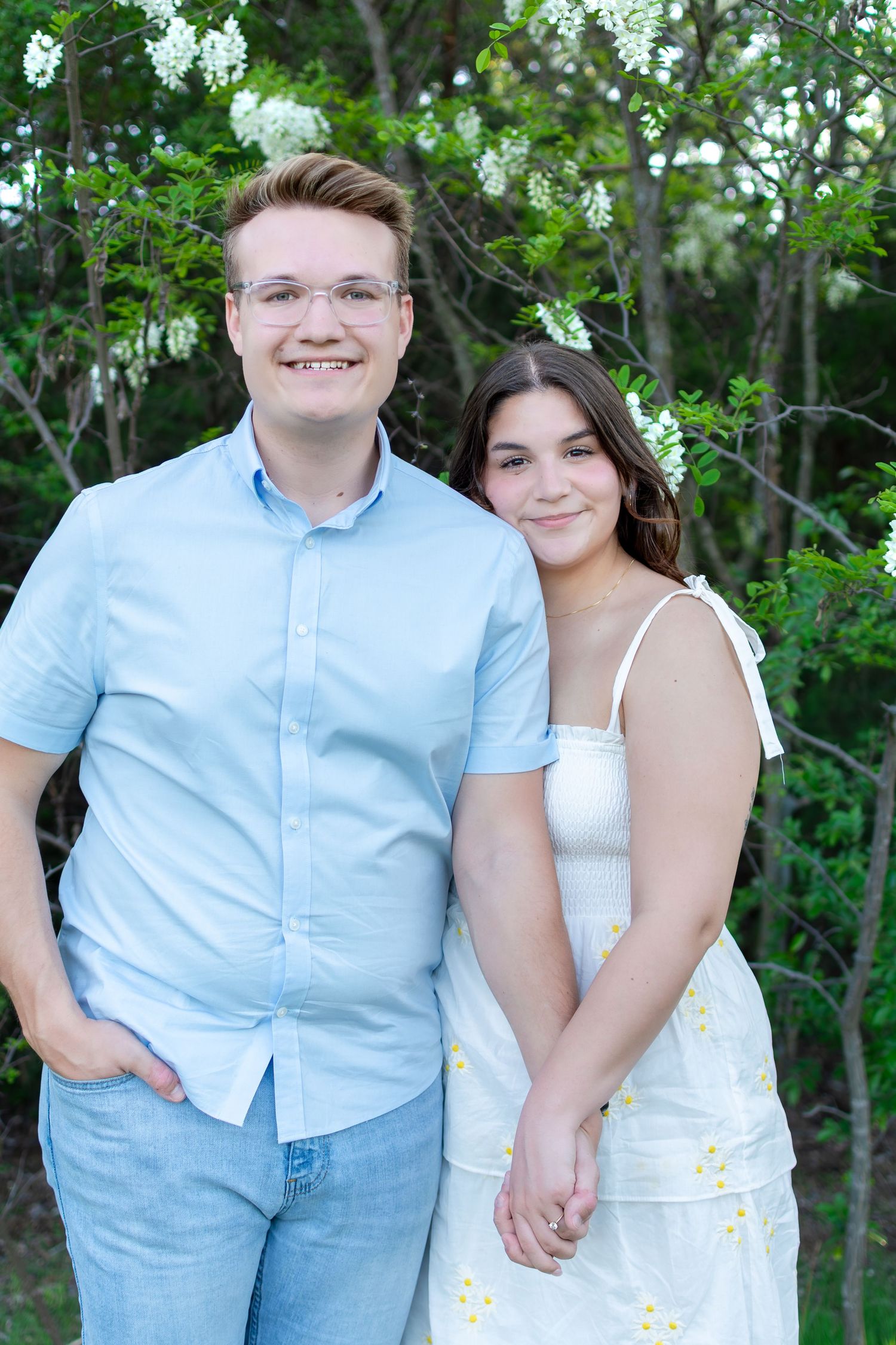 A romantic outdoor photoshoot of a couple in coordinating blue and white outfits against a natural backdrop.