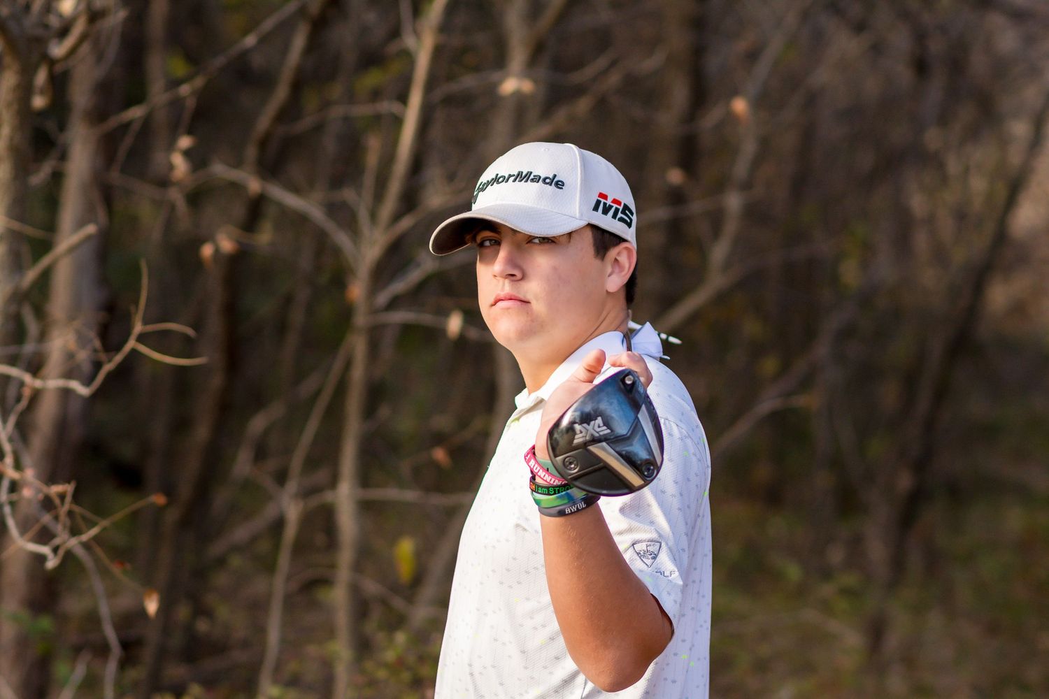 A senior Golf player in a white polo shirt is preparing for a shot on the course.