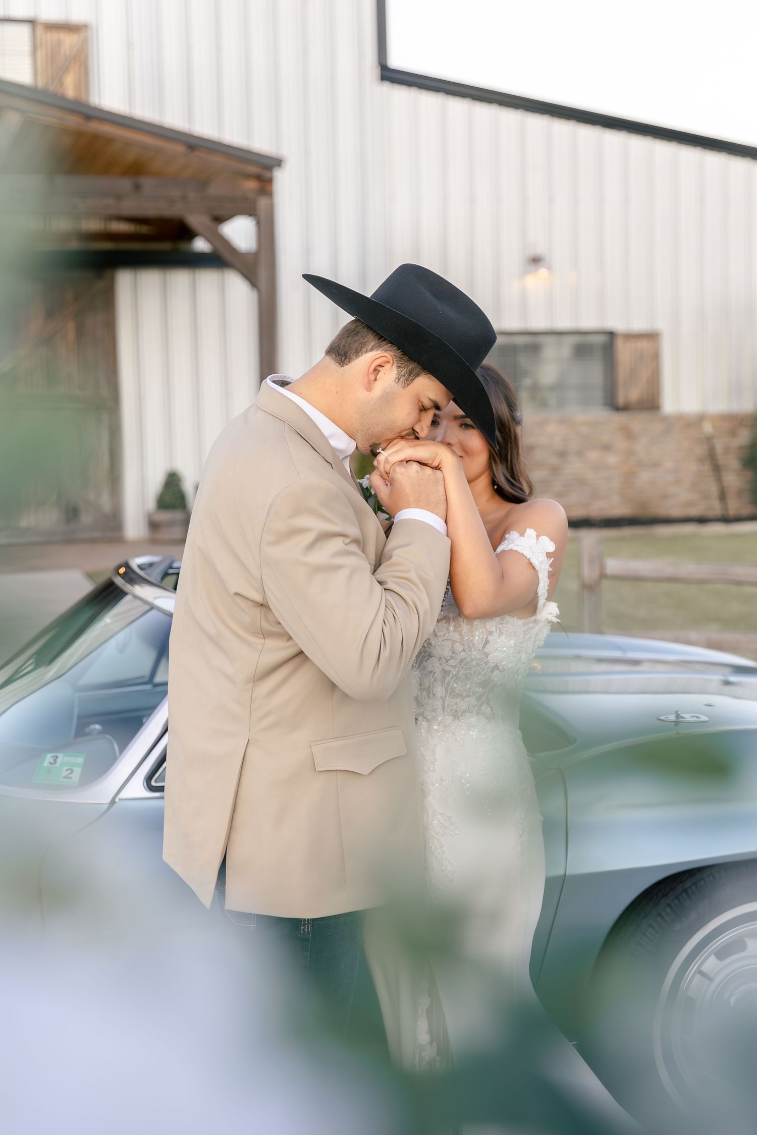 Romantic moment captured near a vintage car with soft, dreamy lighting.