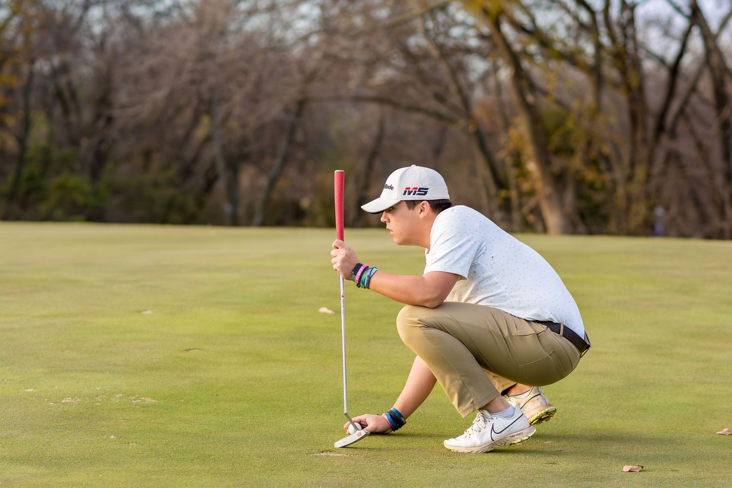 A Senior Golfer crouches to analyze the putting green during a game.