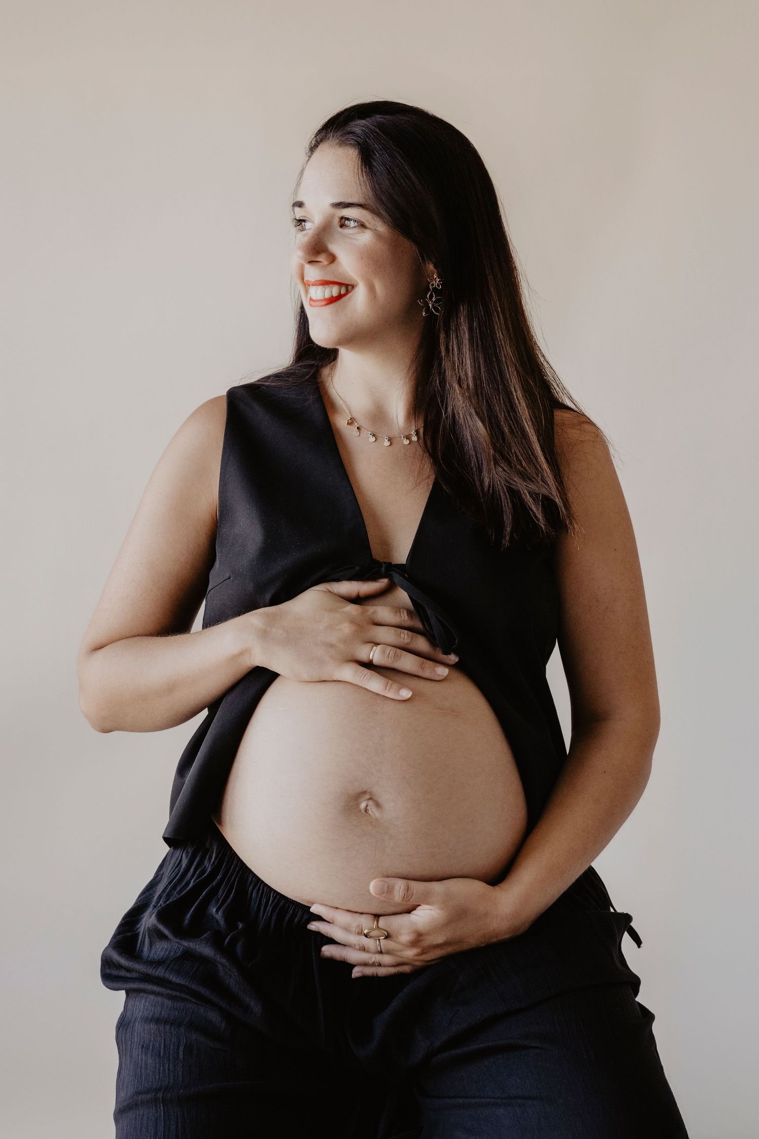 Mujer embarazada sonriendo mientras acaricia su barriga durante una sesión de embarazo