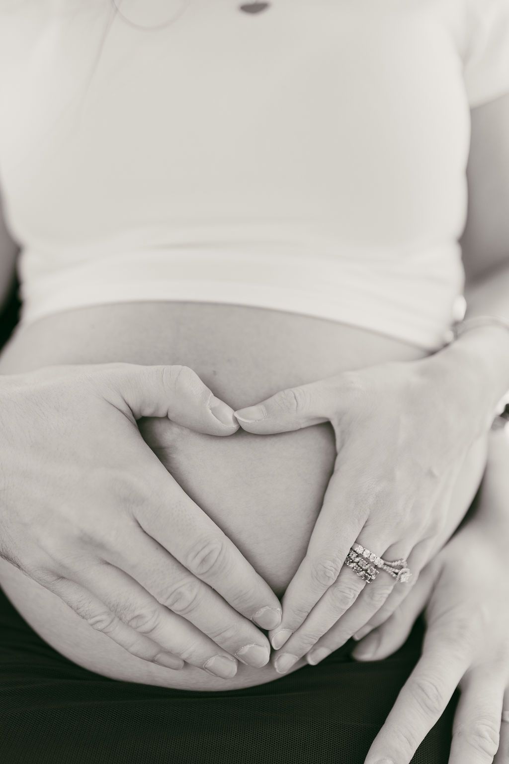 Series of black and white photos showing hands gently cradling a pregnant belly.
