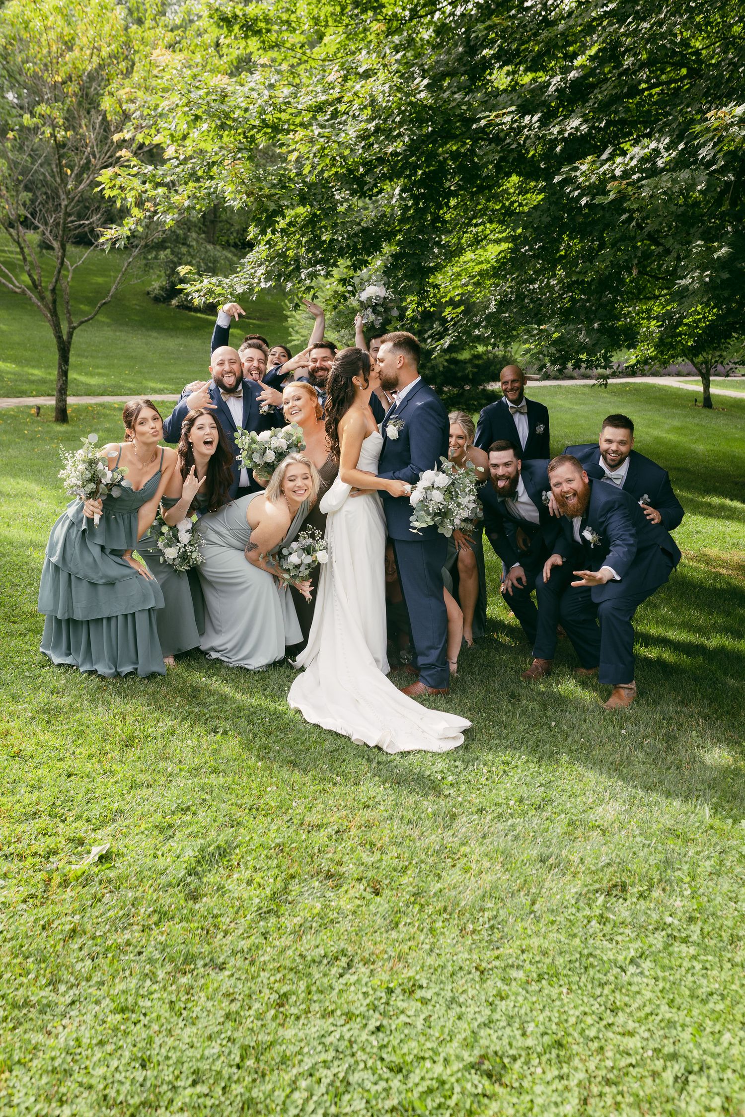 Wedding party lounges on green grass during outdoor photo session.