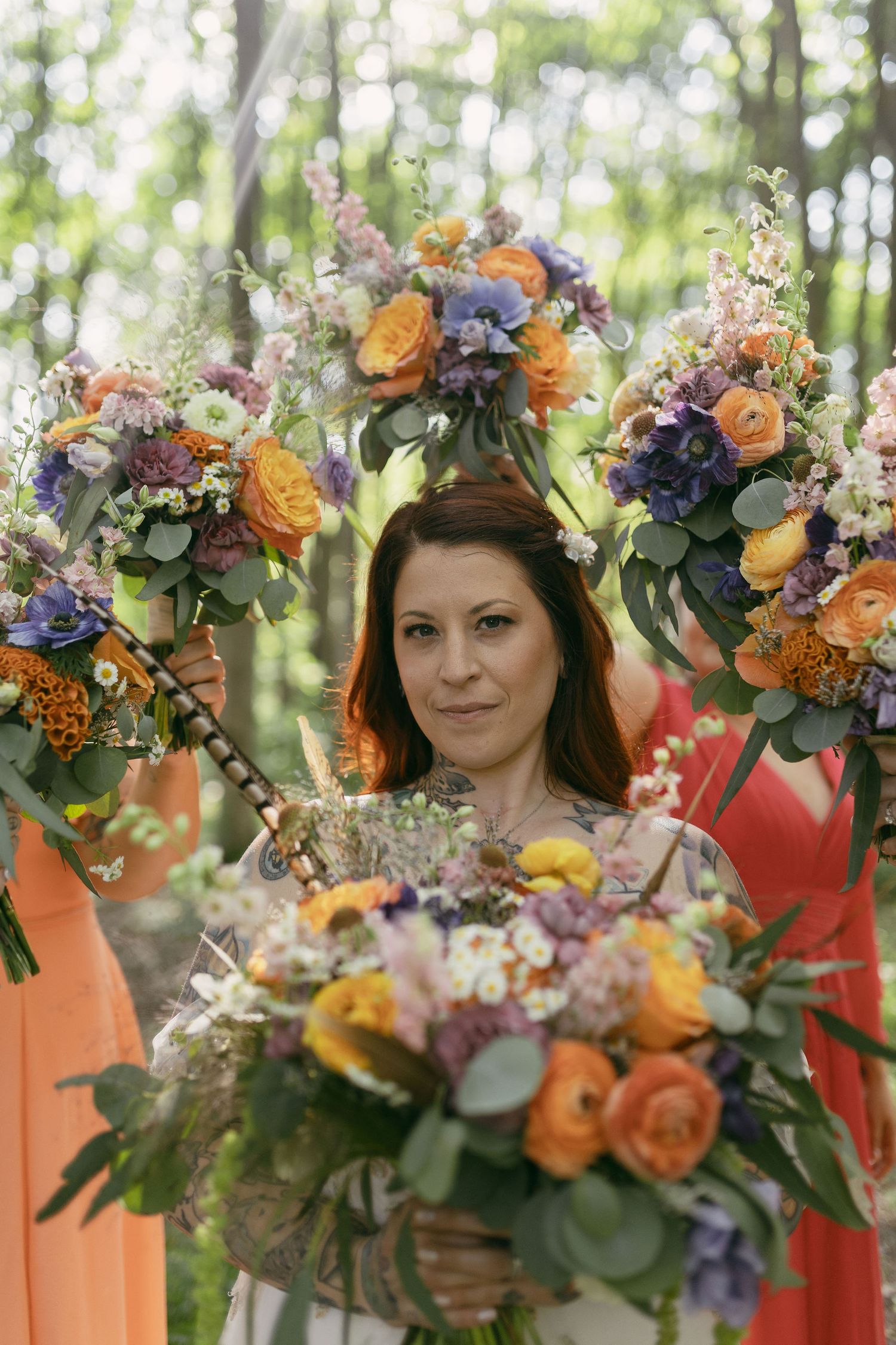 Vibrant floral crowns with orange roses and blue flowers arranged in a row against greenery.