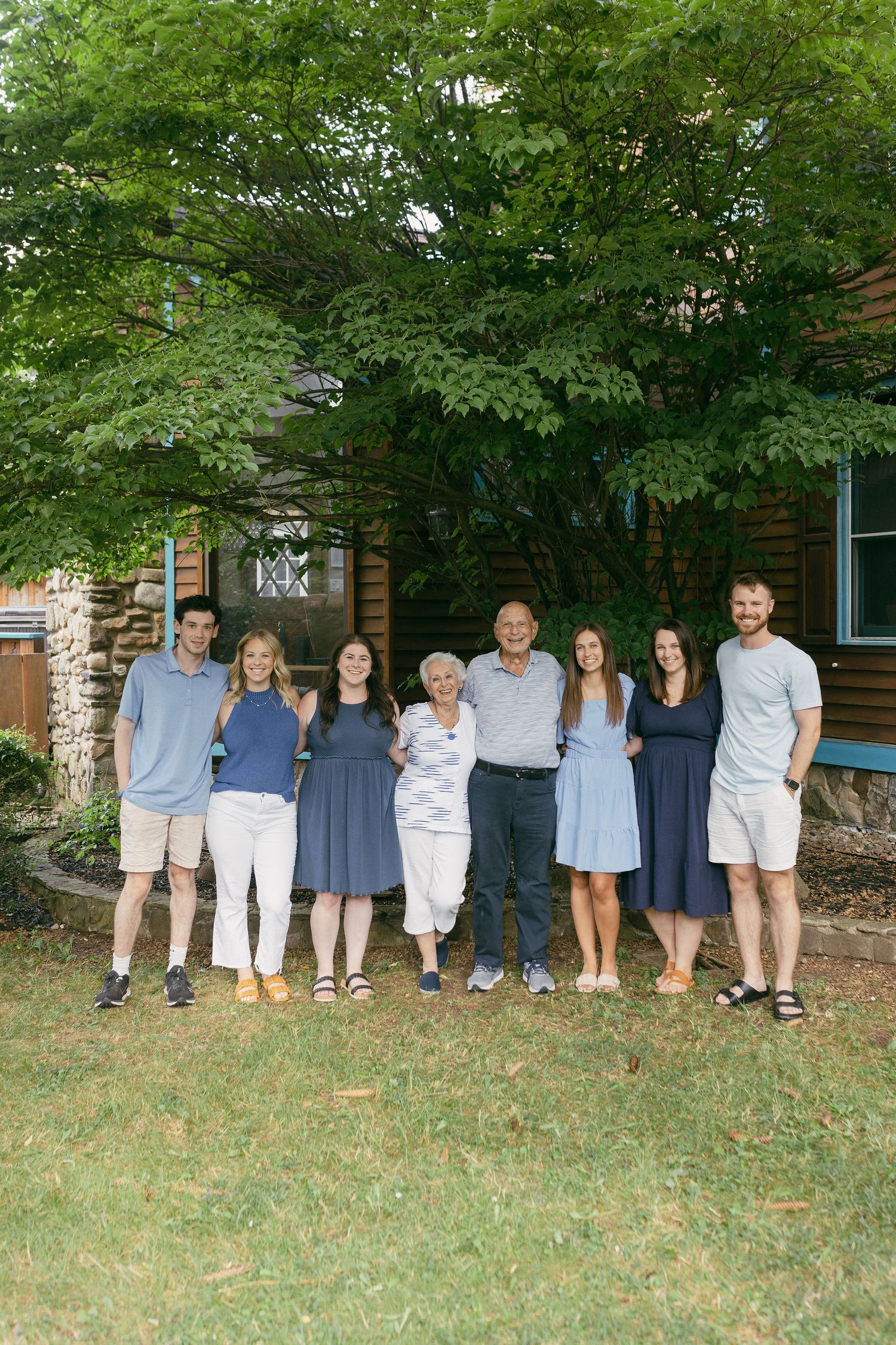 Extended family group lined up against brick building in coordinated outfits.