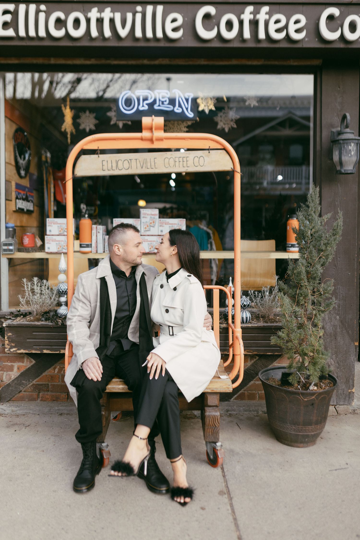 Couple sitting together on a bench outside Ellicottville Coffee Co., sharing a romantic moment in front of the open shop.