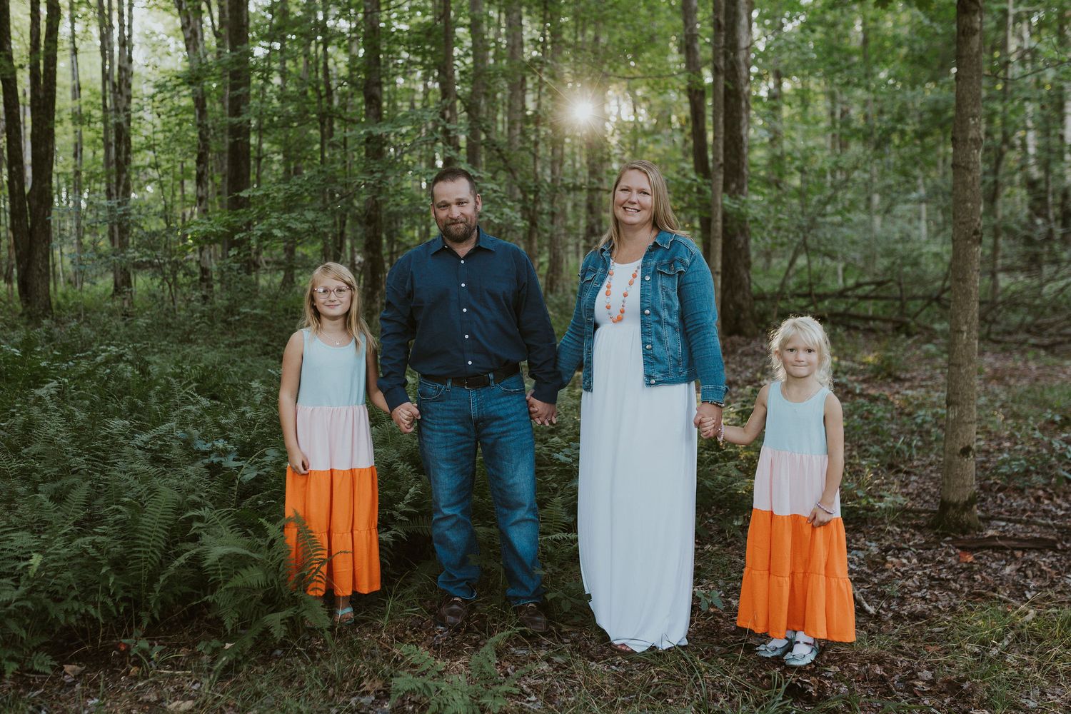 Family walking through a wooded area wearing coordinated white and orange outfits.